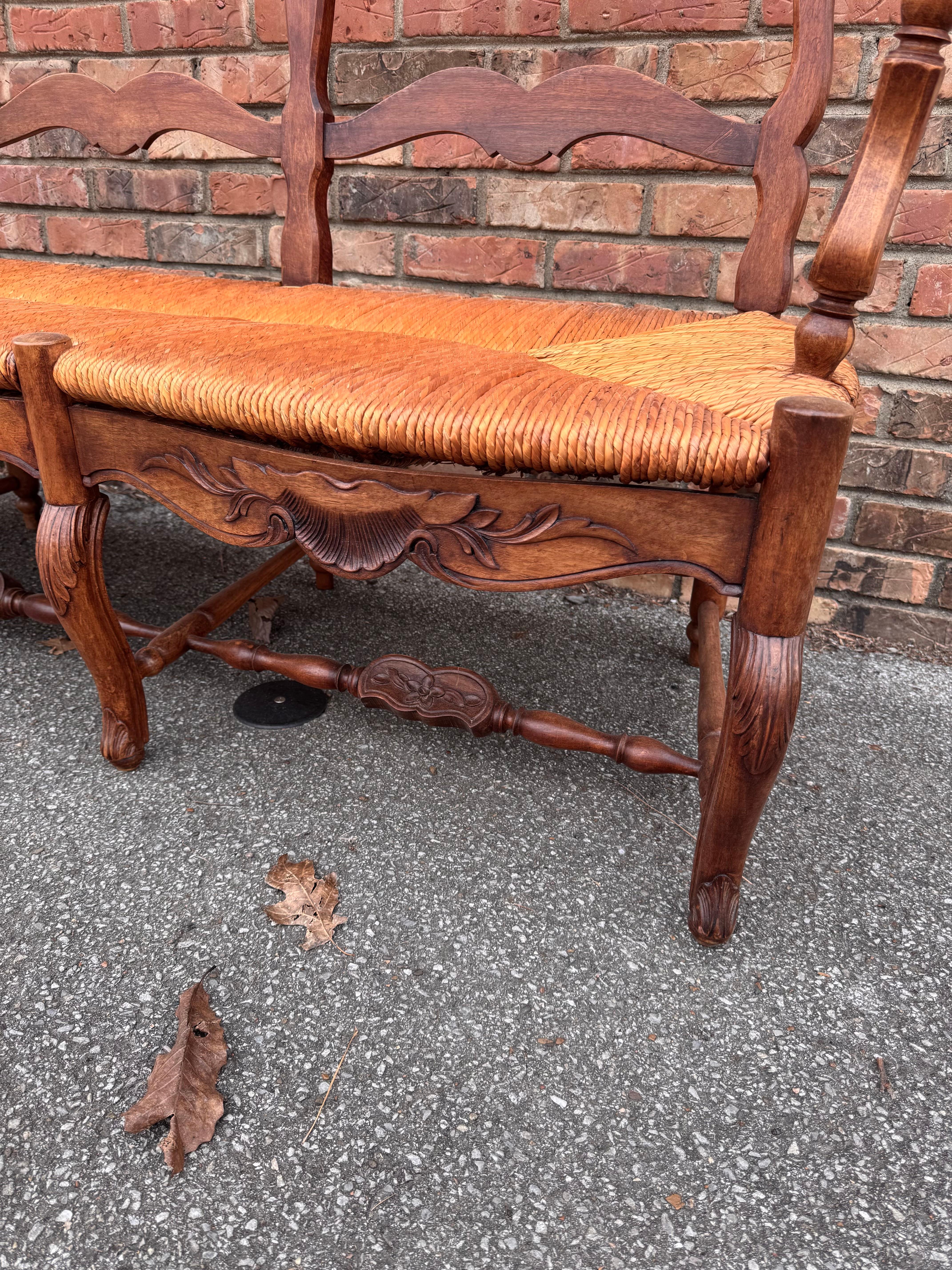 This is an amazing early 19th century French rush seat bench with beautiful age and patina. The leg and arm rest have beautiful curves, as well as the slightly curved back this is truly a one of a kind find. The rush is an excellent condition with