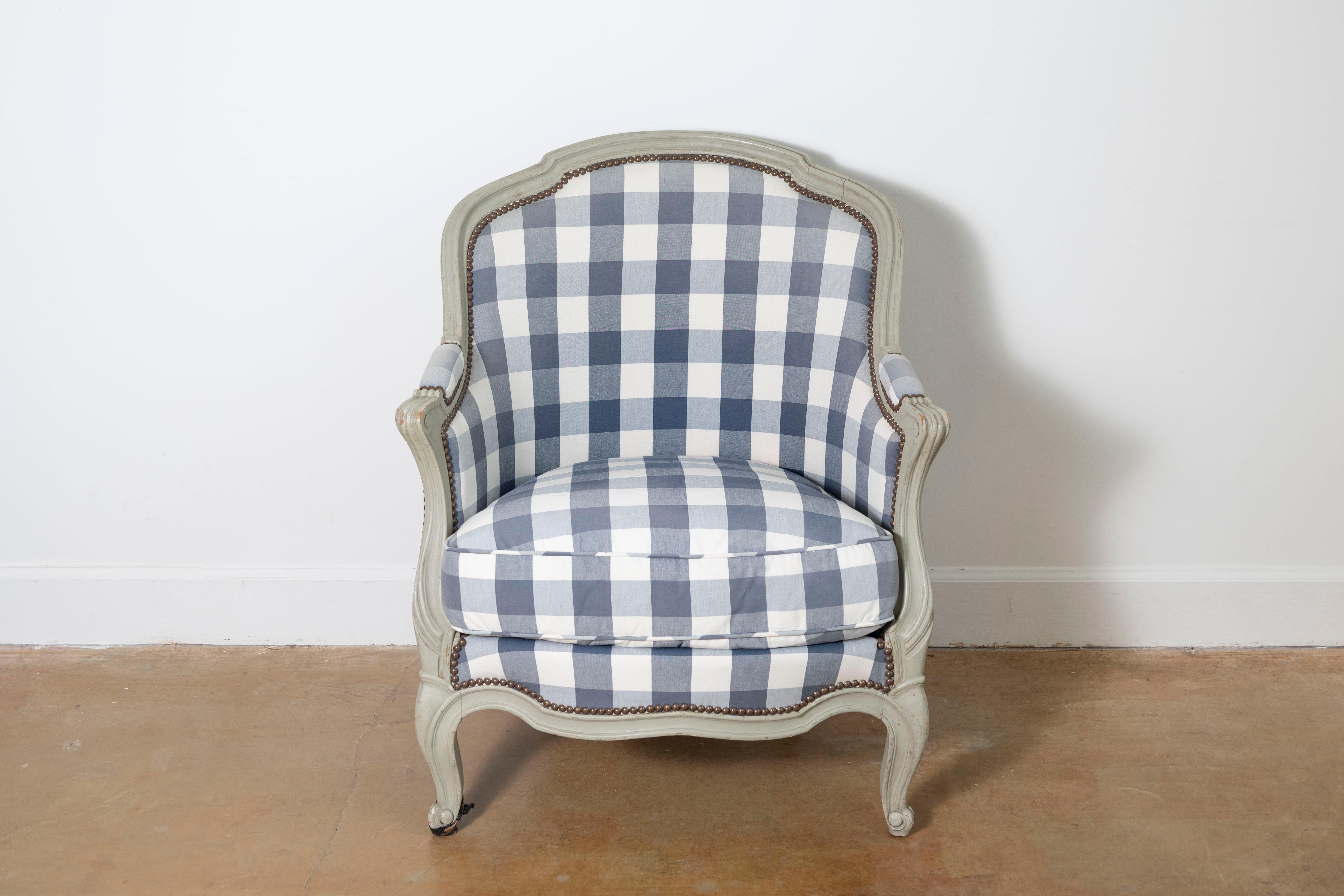 This 19th-century French bergère exudes classic elegance and comfort, making it a timeless statement piece. The carved wood frame, finished in a distressed pale tone, showcases the graceful curves and intricate details characteristic of Louis XV