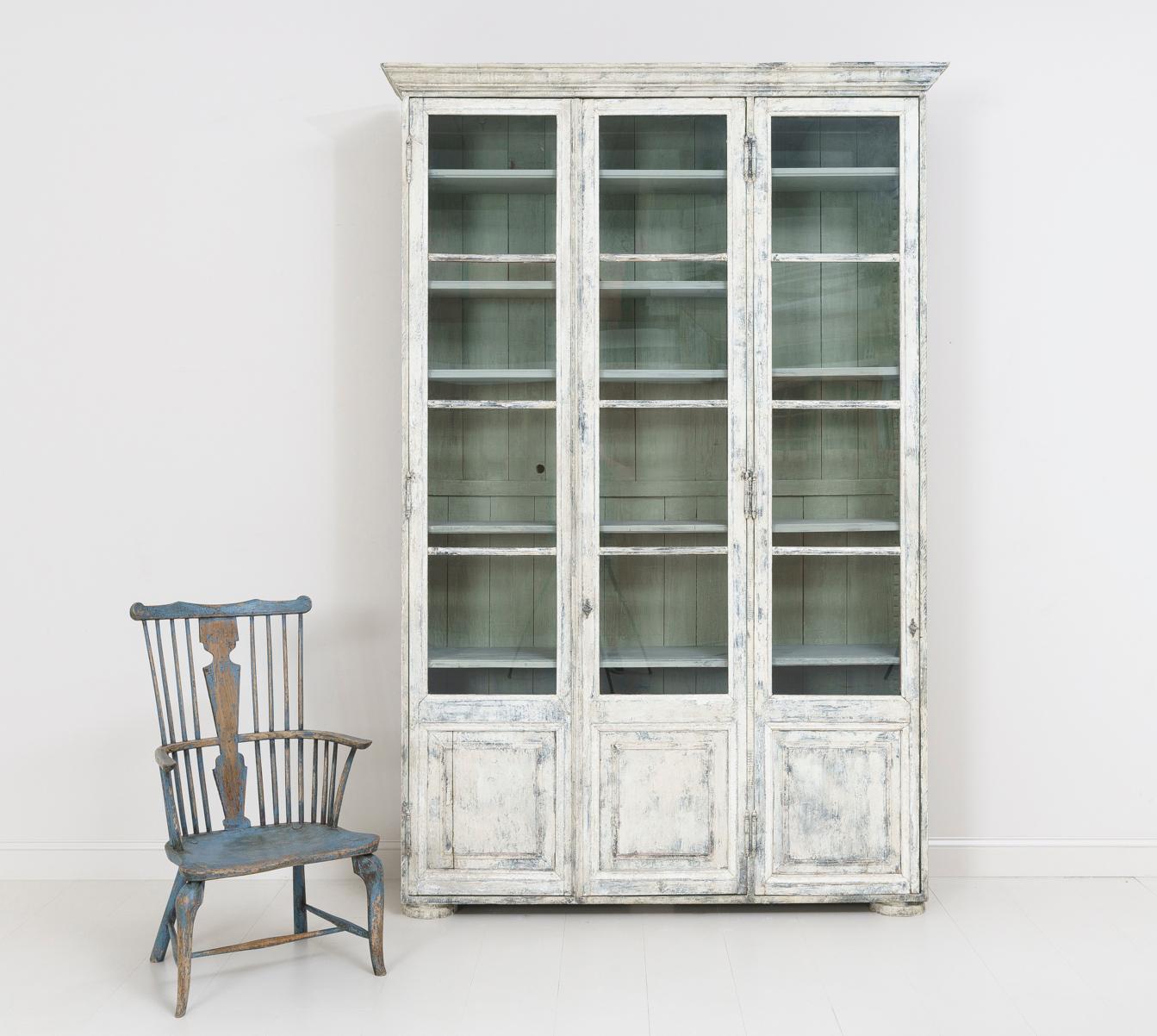 19th century French bibliothèque with original glass and adjustable shelves. This beautiful vitrine cabinet or bookcase is the perfect piece for almost any room. The exterior color is aged white with areas of blue and gray showing through. The