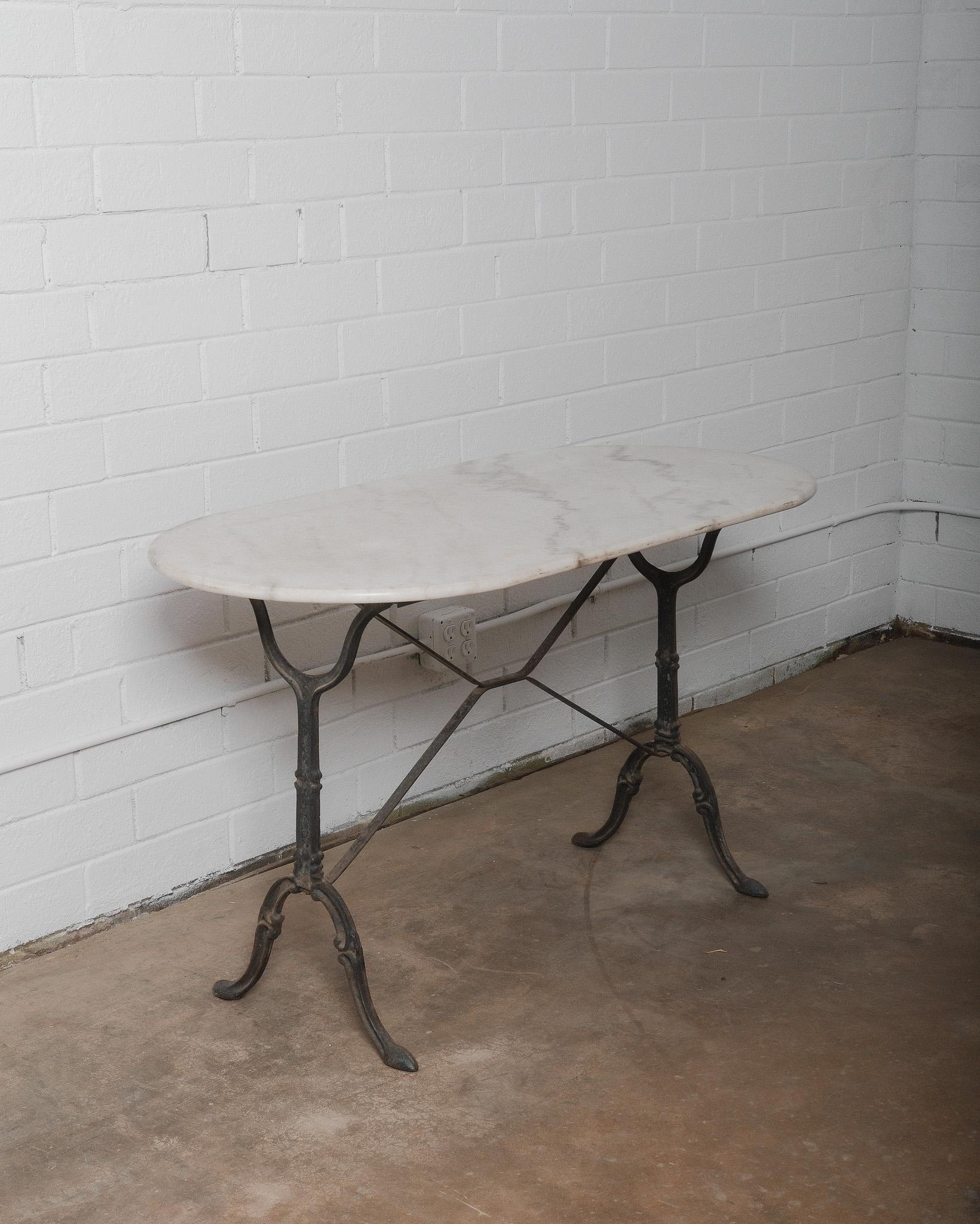 Cette élégante table de bistrot française du XIXe siècle incarne le charme de la culture classique des cafés parisiens. Whiting, avec son plateau en marbre blanc magnifiquement vieilli et subtilement veiné de gris, la table offre un attrait