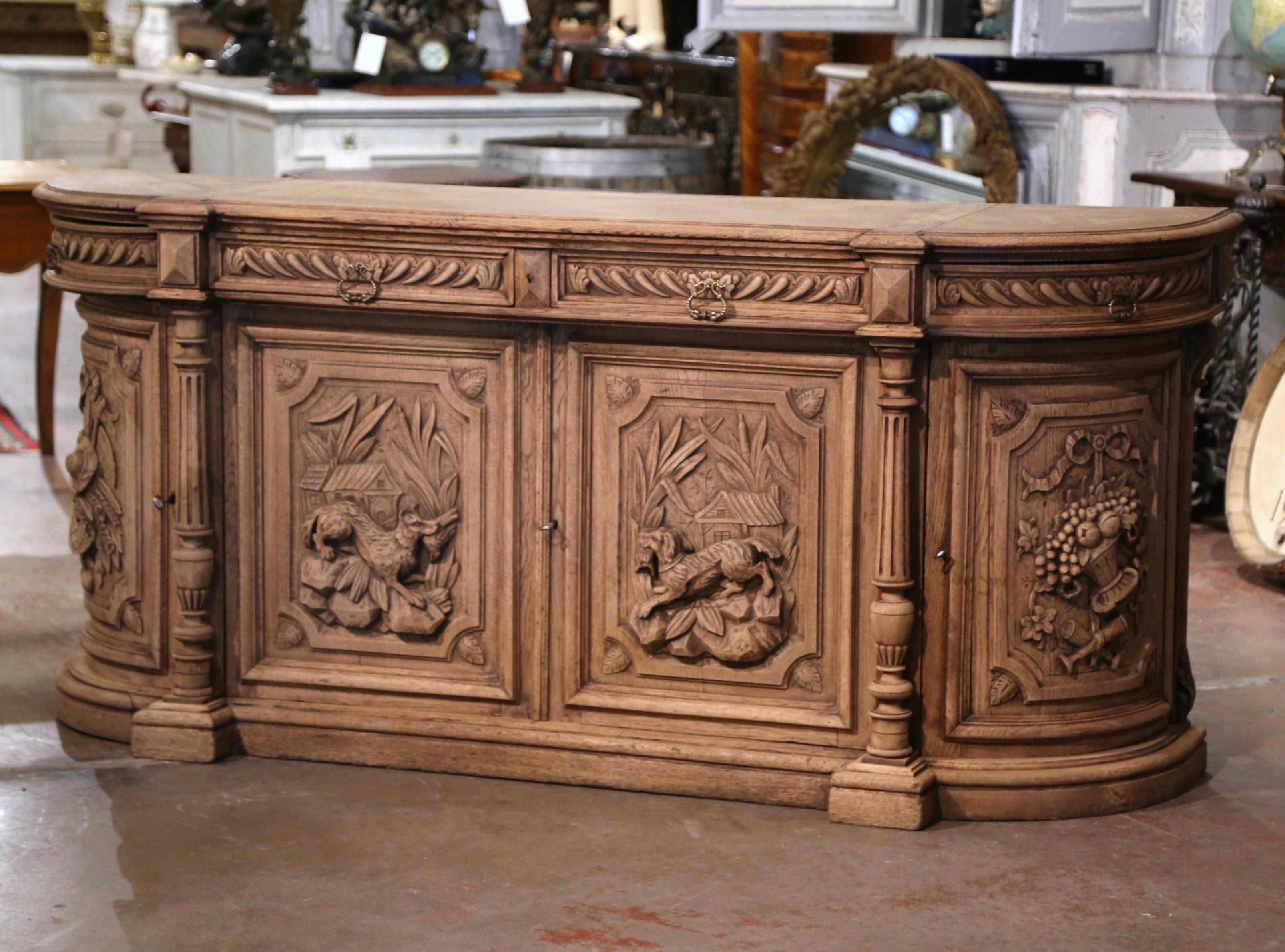 Decorate a ranch or hunting lodge with this important antique four-door sideboard. Crafted in France, circa 1870, the highly detailed buffet with curved sides stands on a wide bottom plinth. The long cabinet features four carved drawers across the