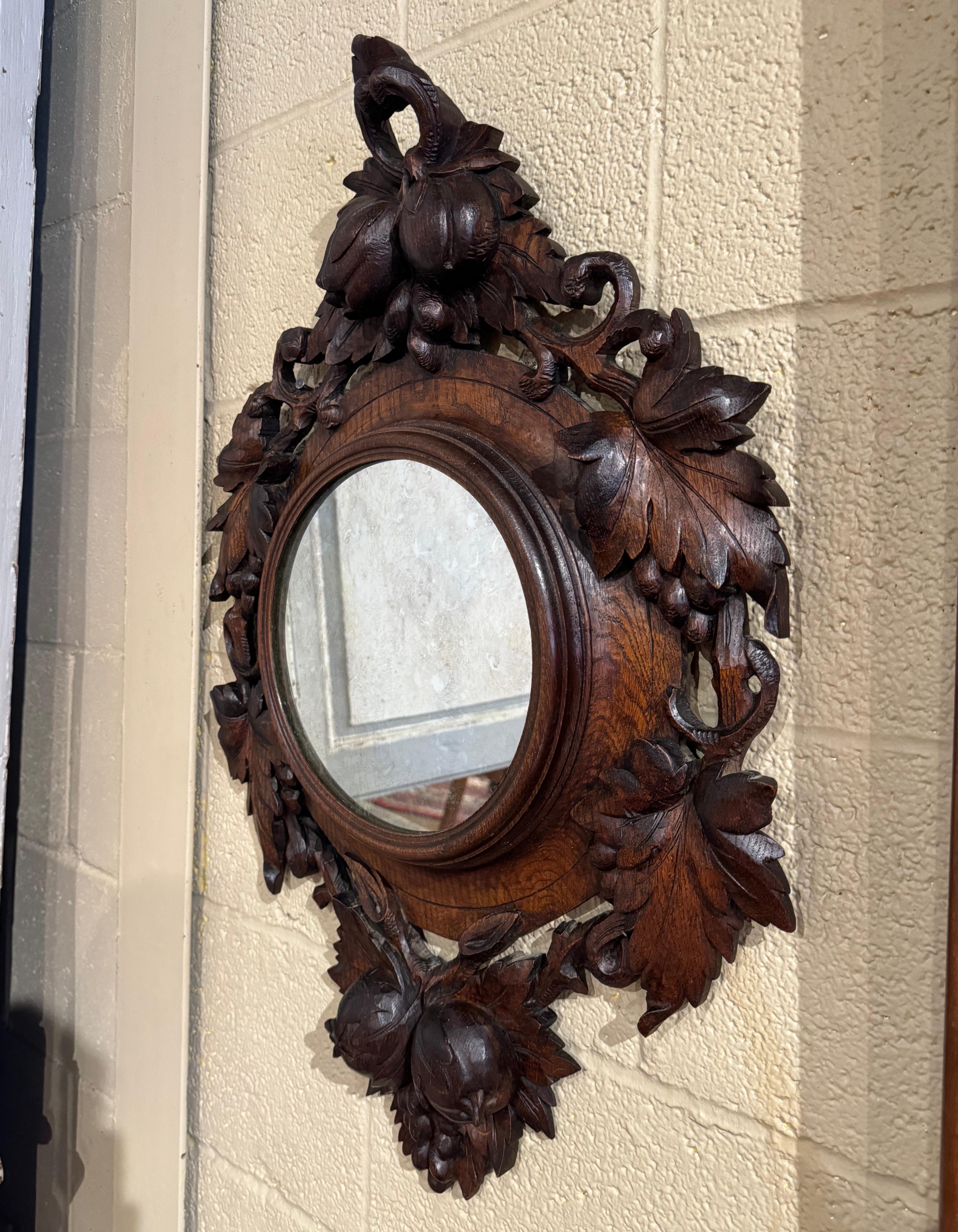 Decorate a den, a study or hallway with this elegant antique mirror. Created in France circa 1880 and built of oak, the oval frame features hand carved and pierced fruit and foliage motifs in high relief throughout the facade. The mirror is in