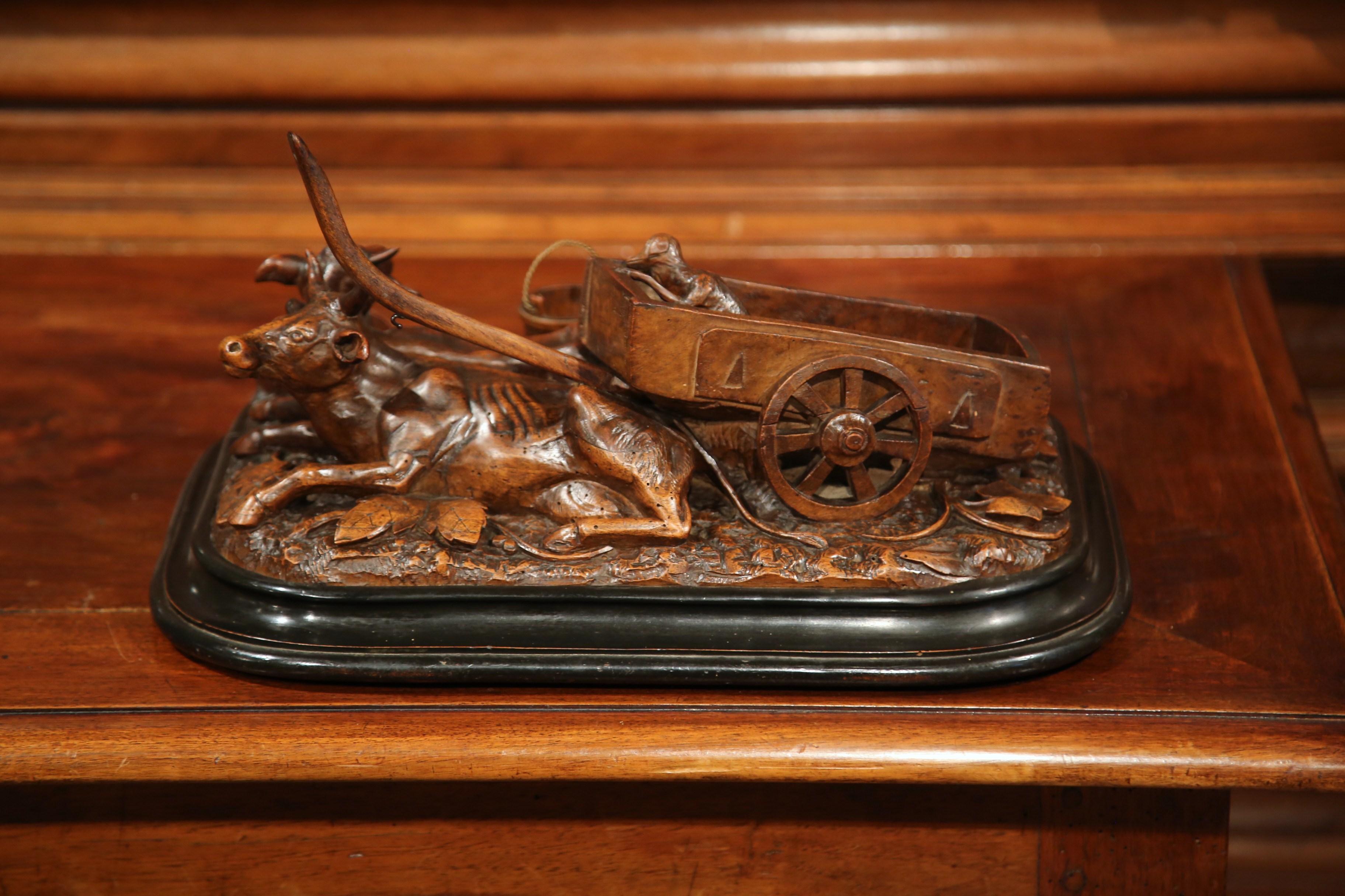 This stately antique Black Forest sculpture composition was carved in France, circa 1860. The sculptural fruitwood work of art features a farm scene with two cows lying down, a wheelbarrow cart with a dog inside; it also features a lizard and a pair