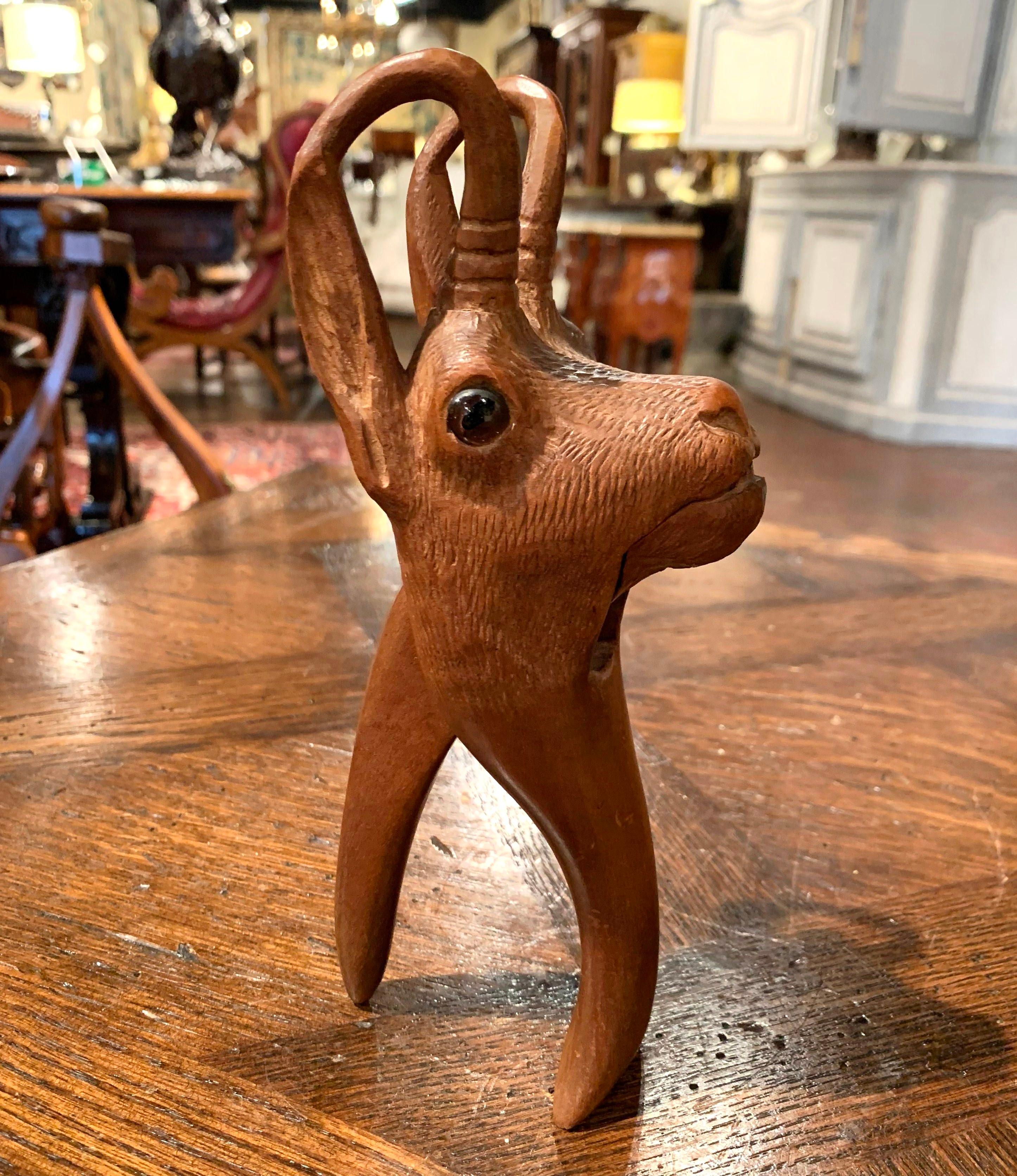 This interesting fruitwood nutcracker was crafted in France, circa 1880; made of walnut, the kitchen utensil features a carved deer head sculpture with horns and embellished with glass eyes. The functional and practical compound lever is in