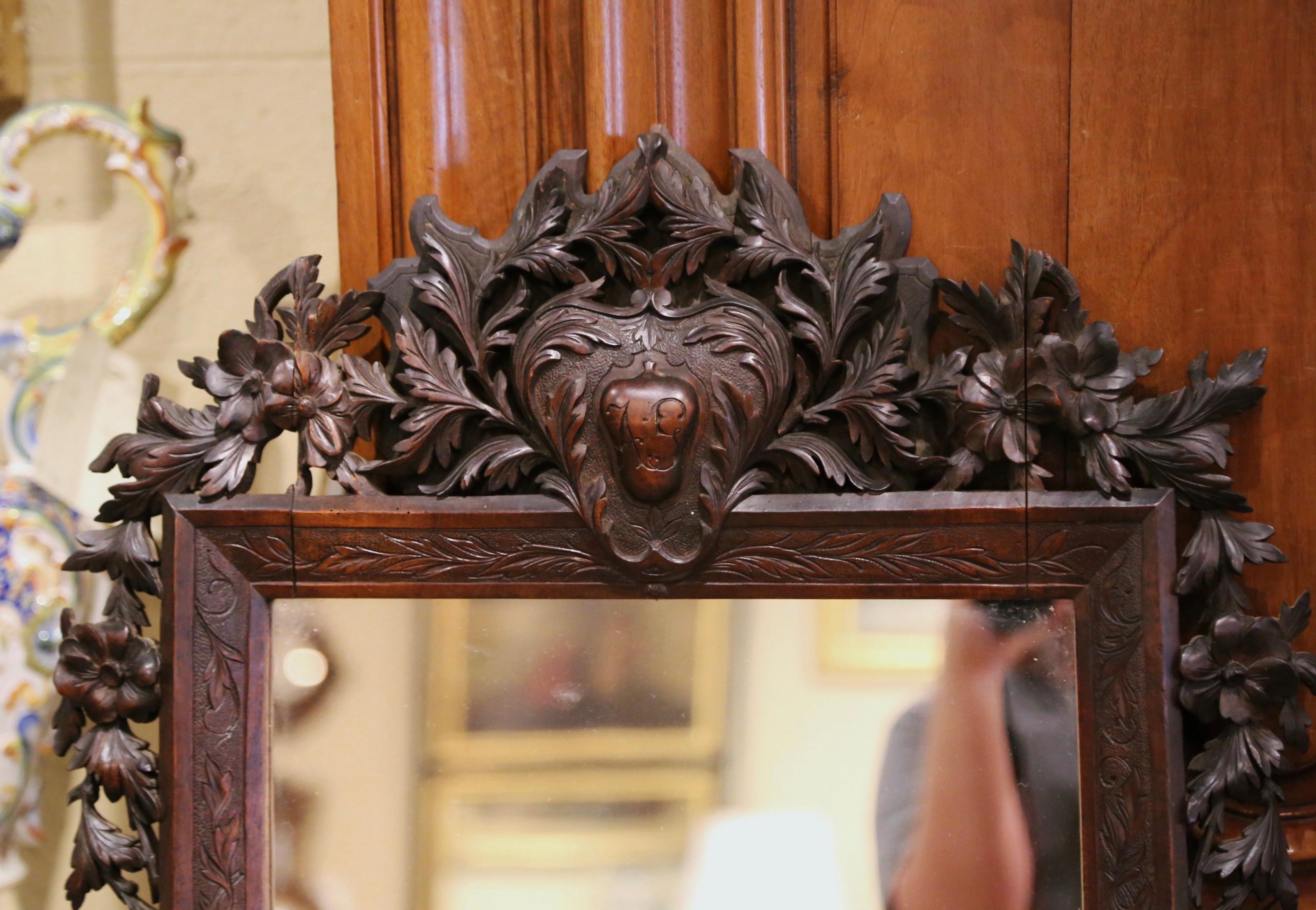 This elegant antique wall mirror was crafted in France, circa 1870. Rectangular in shape, the Black Forest mirror features hand carved floral and leaf motifs throughout embellished with a large shell cartouche at the pediment. The detailed mirror