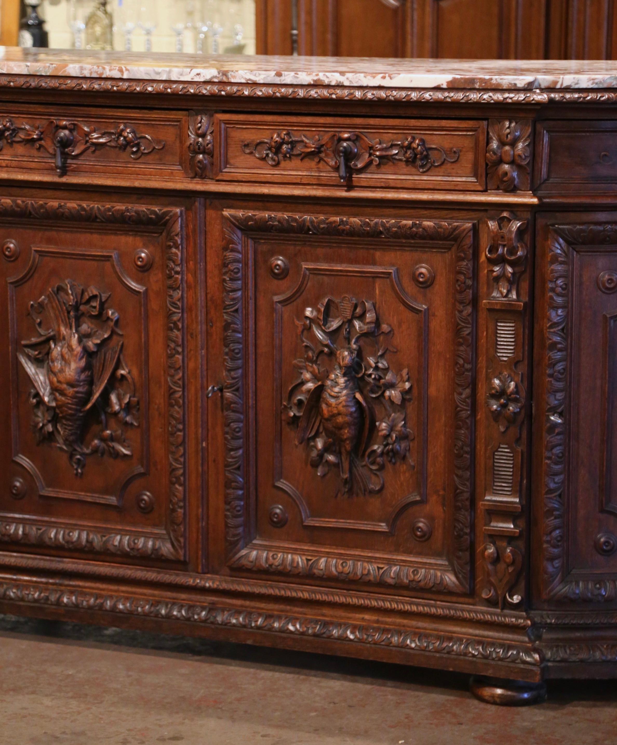 Decorate a ranch or hunting lodge with this important elegant antique four-door sideboard. Crafted in France, circa 1870, the highly detailed buffet with curved sides stands on bun feet over a wide bottom plinth. The long cabinet features four