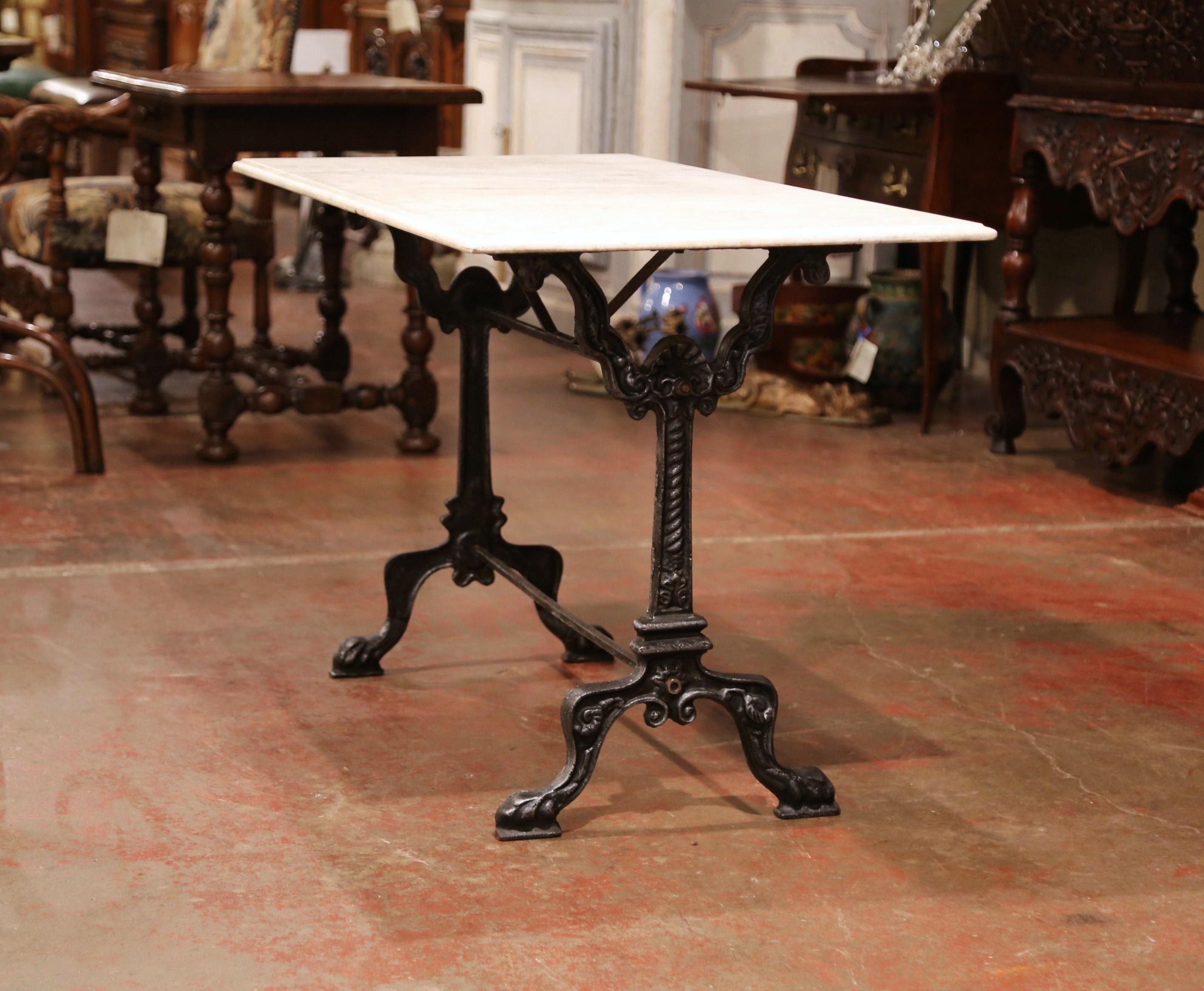 Crafted in France circa 1890, this versatile black iron and white marble table could be used in a variety of settings in your home. The traditional, elegant table sits on two pedestals with scroll legs and paw feet, joined with a double decorative