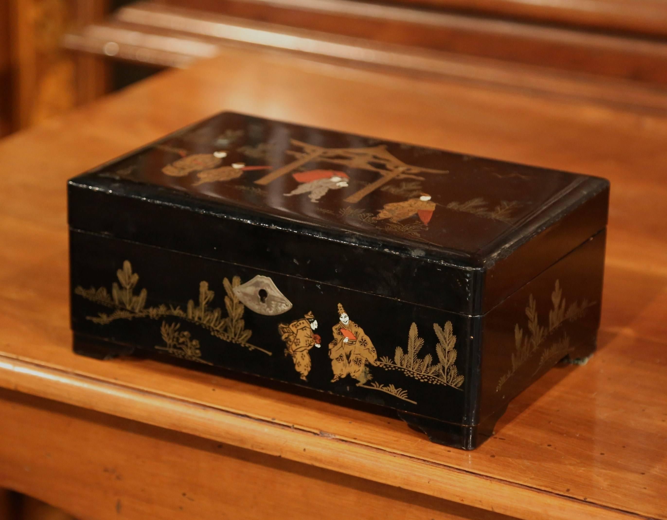 Top your vanity with this interesting makeup box; crafted in France, circa 1880, the black lacquered box is decorated on the outside with illustrative chinoiserie motifs embellished with gold and silver leaf accents. Inside, is a music box in