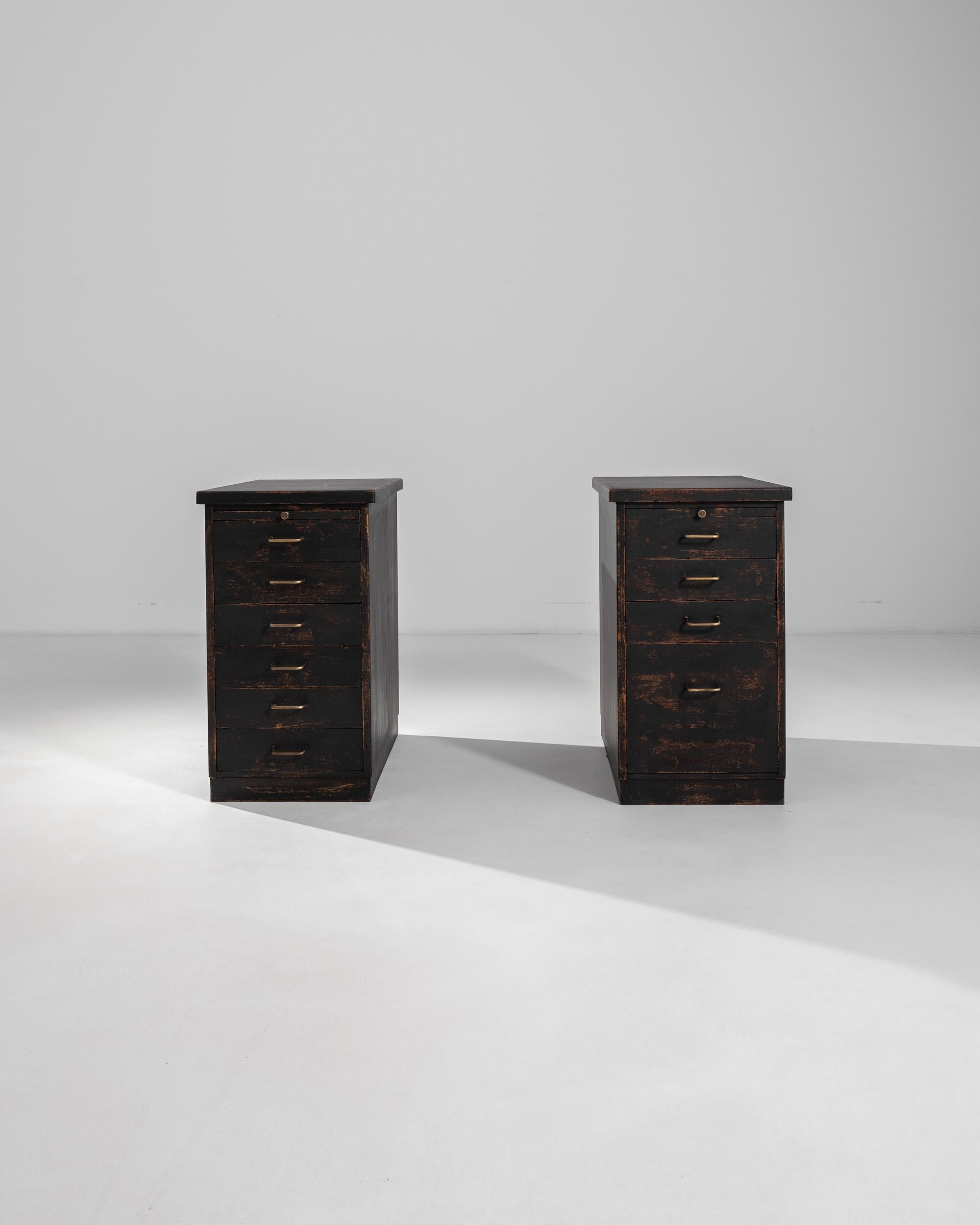 A pair of 19th century wooden drawer cabinets, this patinated ensemble features each one an arrangement of six and four drawers, topped by a practical retractable surface. Elevated at two feet and a half, the wooden chest of drawers exhibit a dark