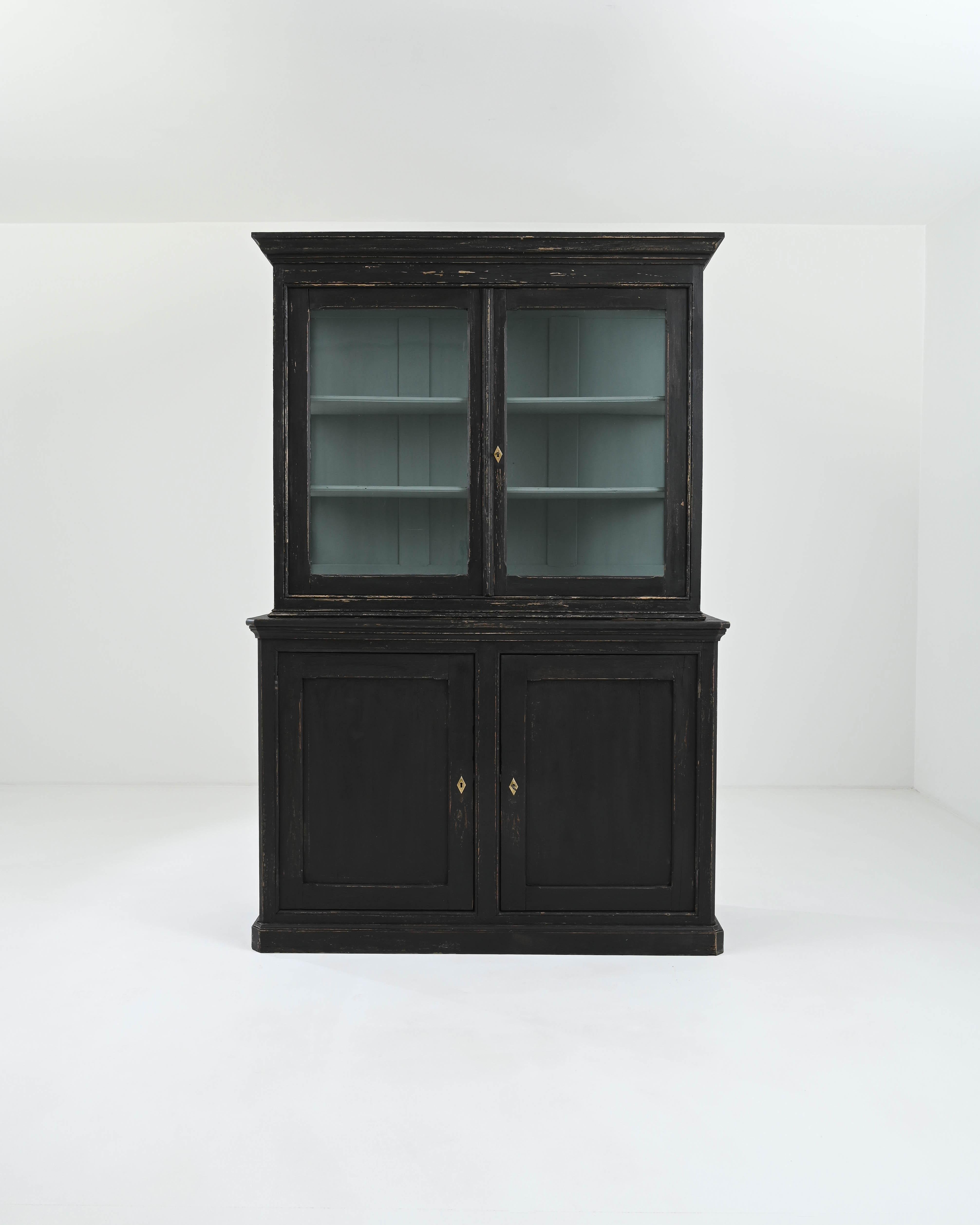 This elegant vitrine à deux corps, hand-crafted in France during the 19th century, exudes a flawless symmetry evident in the plinth base's contours; geometric carvings of the panels; and pointed edges of the molded cornice, mirrored in the corners