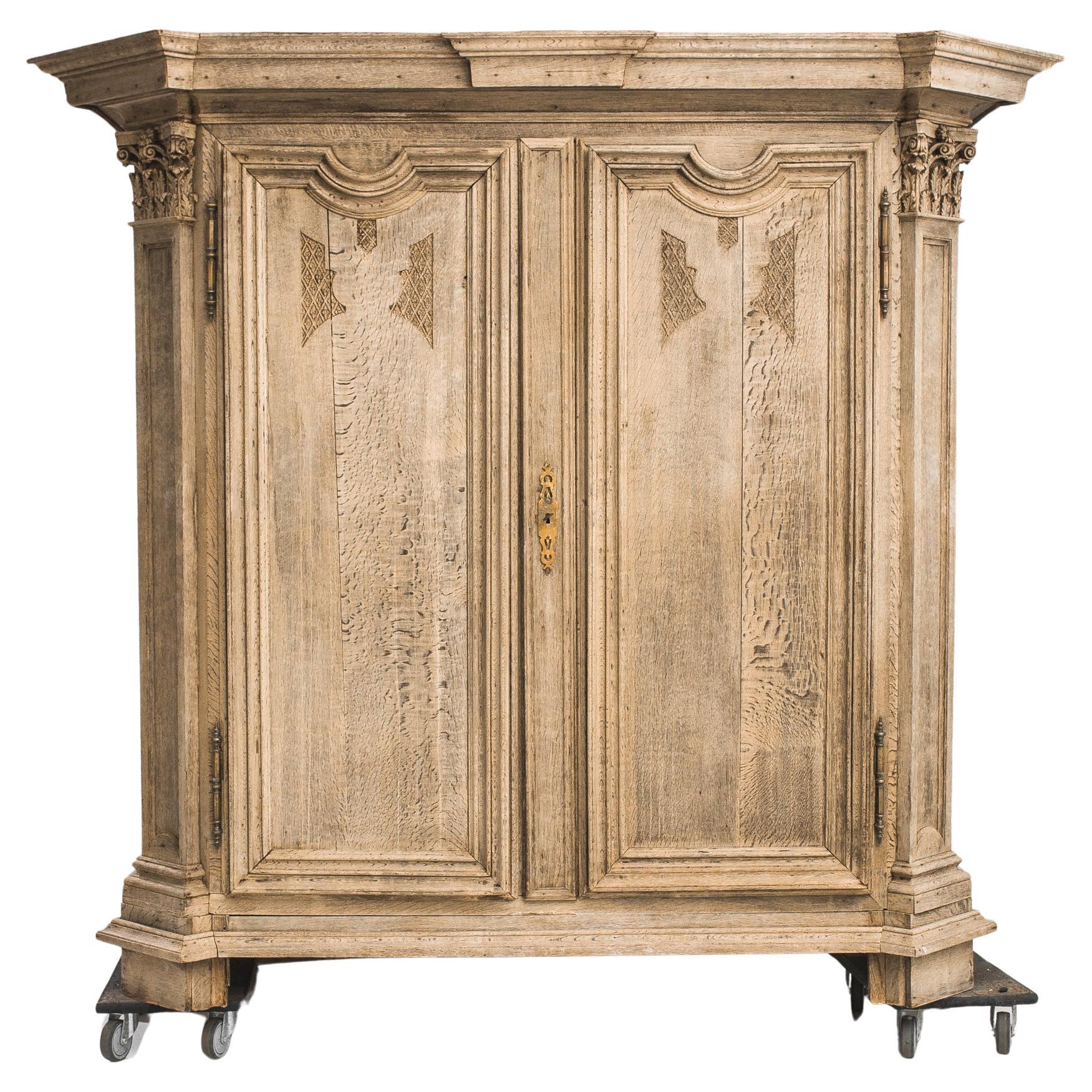 Impressive in stature, the 19th Century French Bleached Oak Armoire exudes grandeur and timeless allure. Opening its two doors reveals a spacious interior boasting four shelves, providing ample storage. The armoire is crowned with molding at both