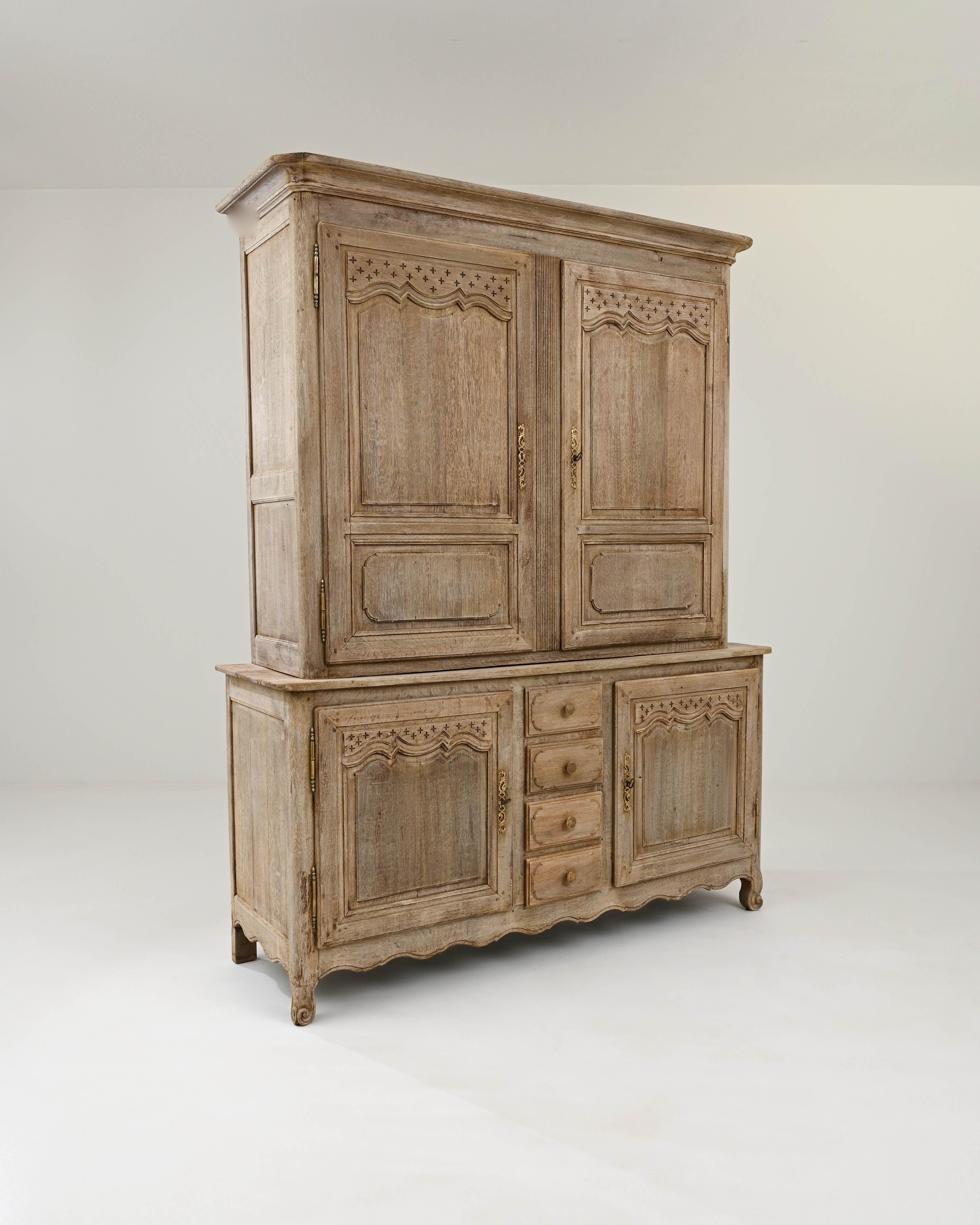 Handcrafted from oak in France circa 1820, this robust deux corps cabinet offers plenty of storage space and an elegant style. The wider bottom cabinet gives the piece a sense of gravity,  decorated with a scalloped skirt and elevated on short