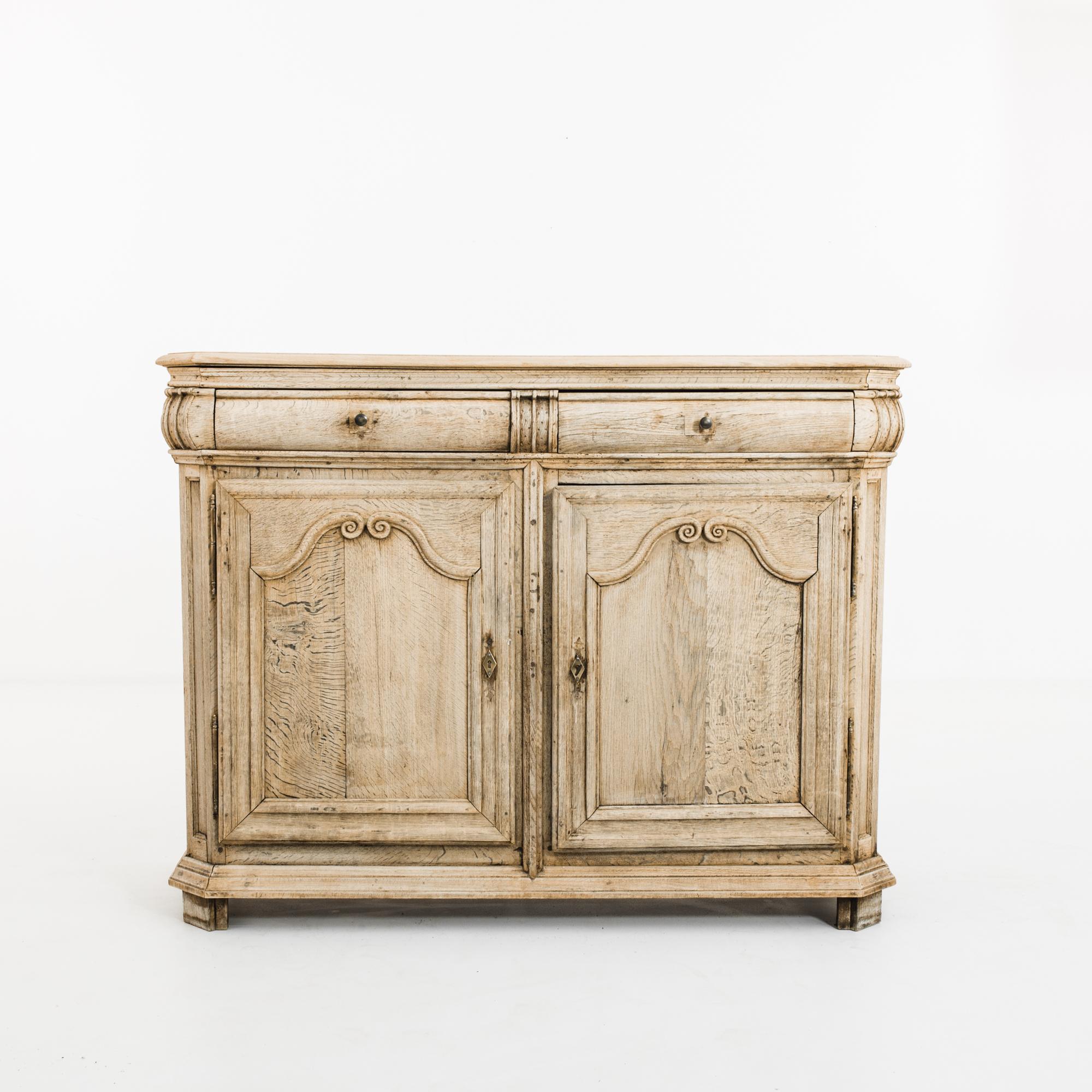 This antique bleached oak buffet was made in France, circa 1800 and imparts the rustic charm of a farmhouse with its light finish. It features chamfered corners and paneling with arches composed of scrolls, highlighting the exceptional workmanship