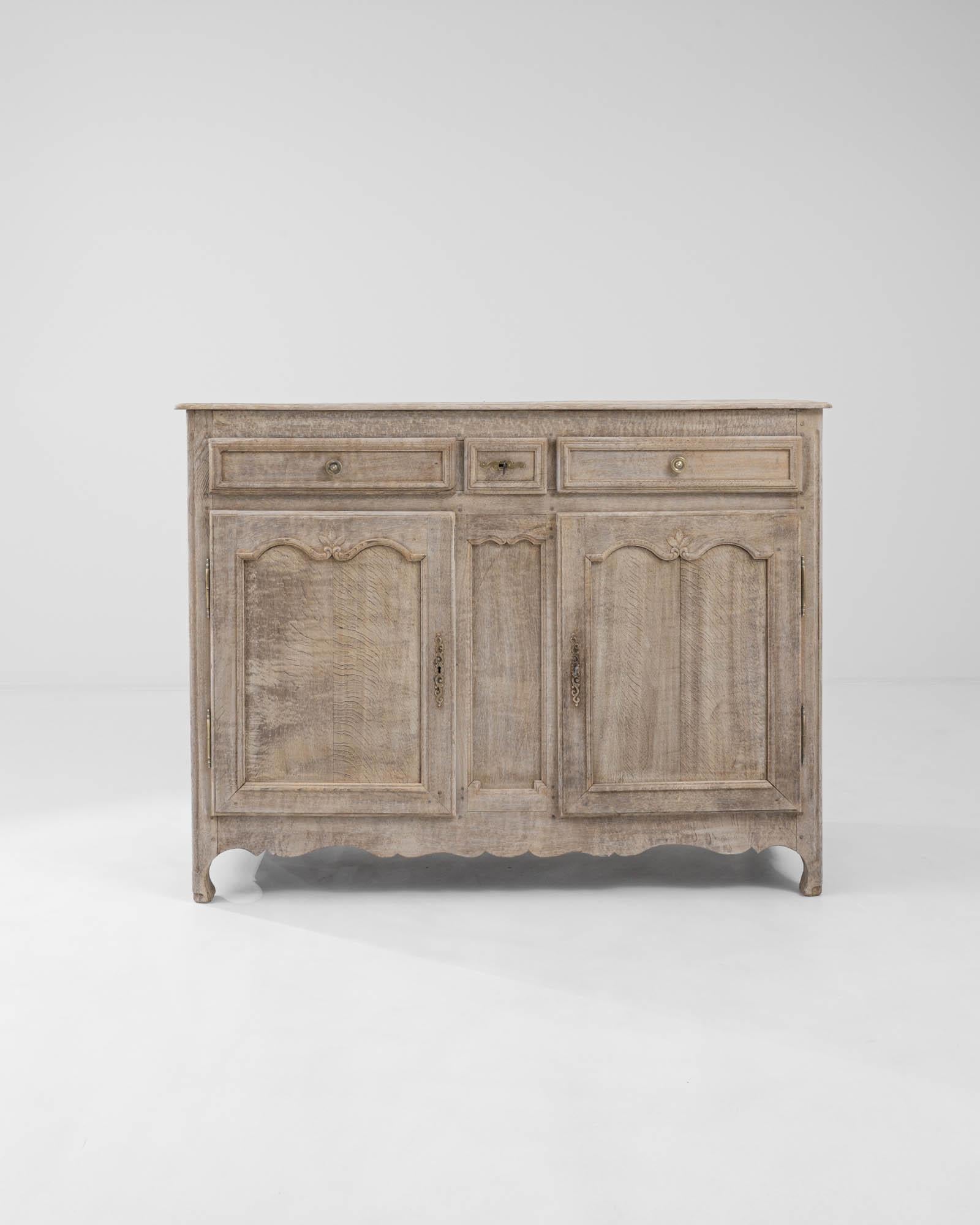 A wooden buffet made in 19th century France. Presenting itself with a dignified ornateness, a cheery glow emits from the finely sculpted oak of this buffet. The natural oak grain has been restored through a delicate bleaching process which both