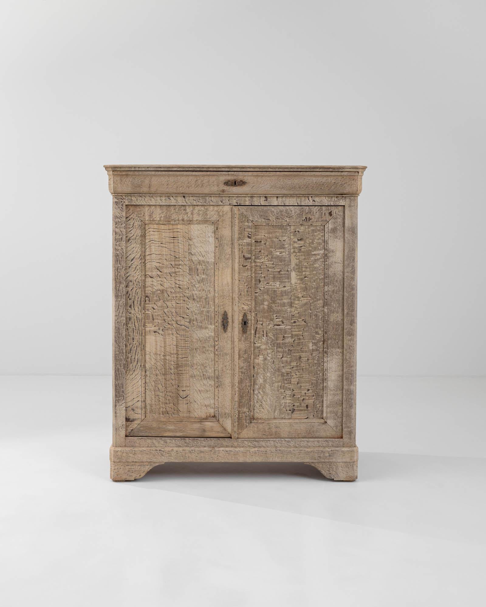Made from refined European oak in 19th-century France, this oak buffet boasts graceful rippling patterns in the bleached wood, giving it a distinctive appeal. The top shelf, concealed within the molded cornice, complements the ogee bracket feet