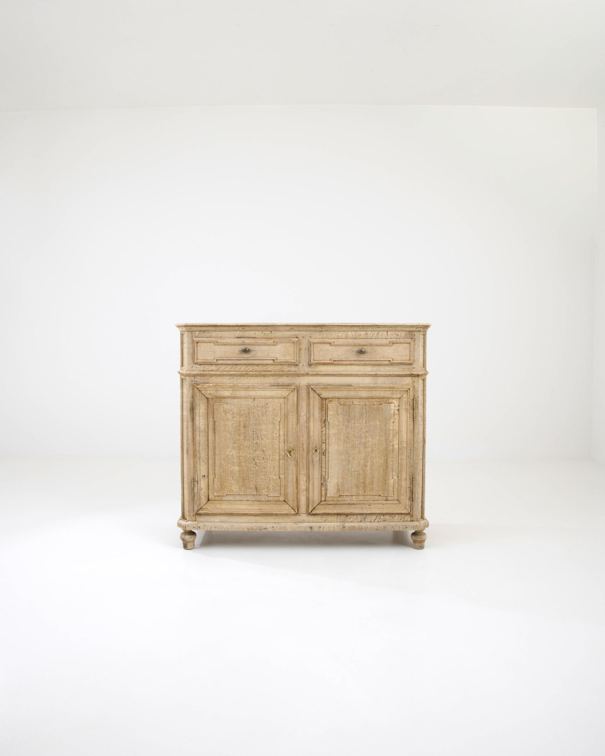 This oak buffet was handcrafted in France in the 19th century. The linear carvings adorning the set of drawers and two panel doors stylishly juxtapose the organic materiality of the oak, creating a balanced composition. The minimalist handles and