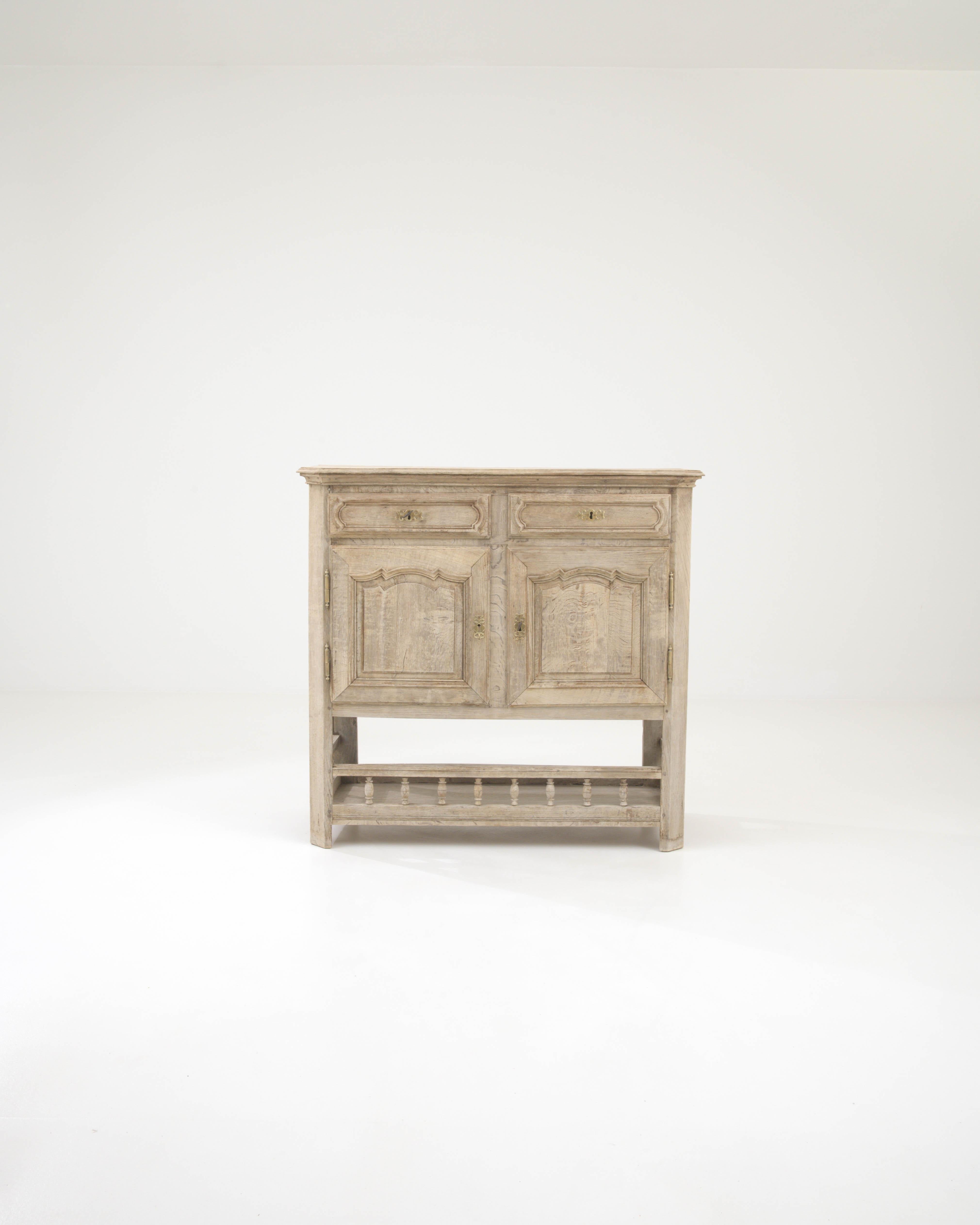 Step back in time with the exquisite 19th Century French Bleached Oak Buffet, a statement piece resonating with the charm and sophistication of a bygone era. This elegant buffet boasts a beautifully weathered finish, highlighting the natural beauty