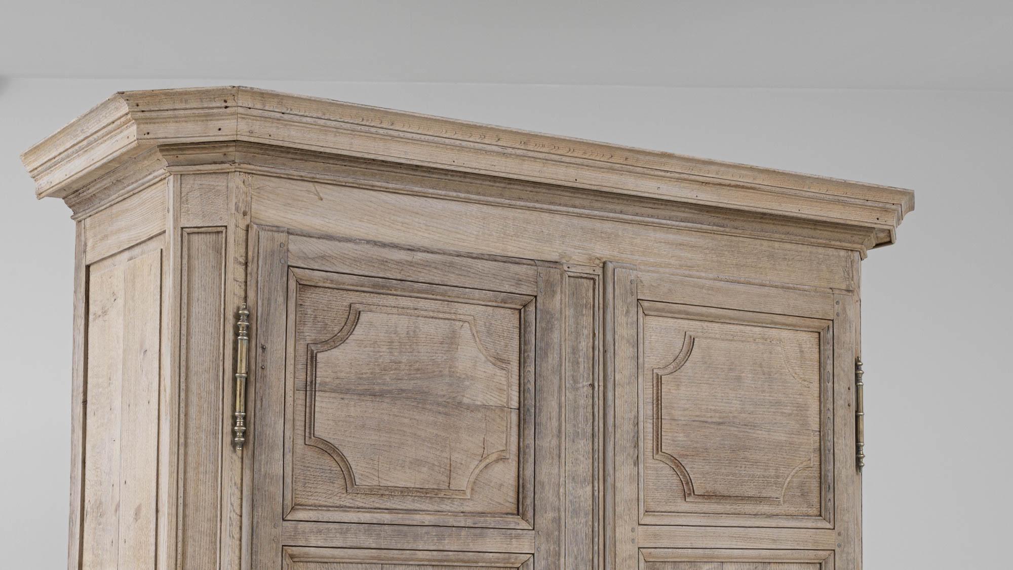 Impressive in stature, this antique oak cabinet is built elegantly in design. Crated in France during the 19th century, this cabinet is beautifully designed from its crown molding and hand-carved wood. Within this antique cabinet, dual doors and two