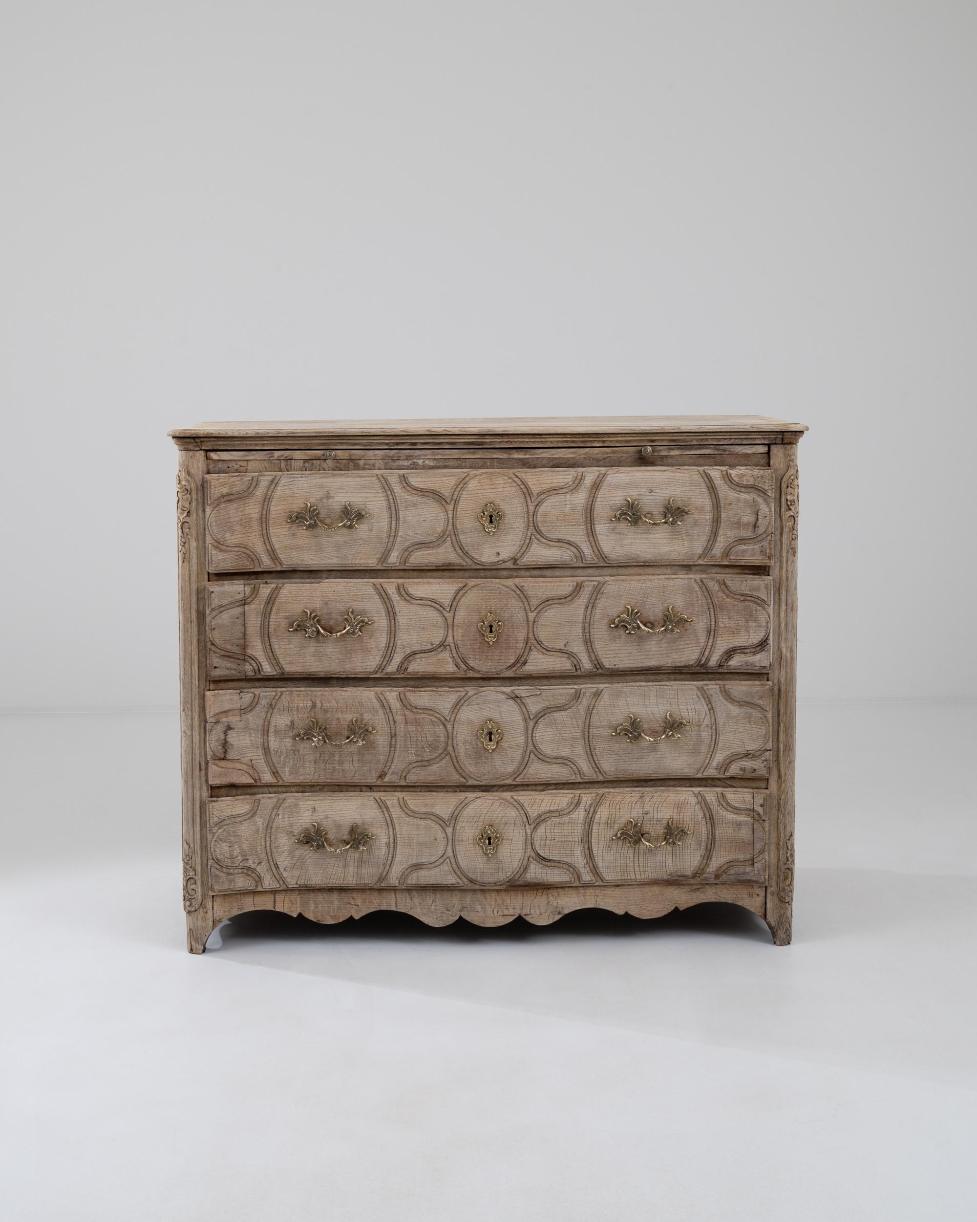 Built during the 19th century in France, this sturdy bleached oak dresser showcases four spacious drawers adorned with distinctive serpentine patterns. The meticulously carved ornate elements on the sides of the chest beautifully complement the