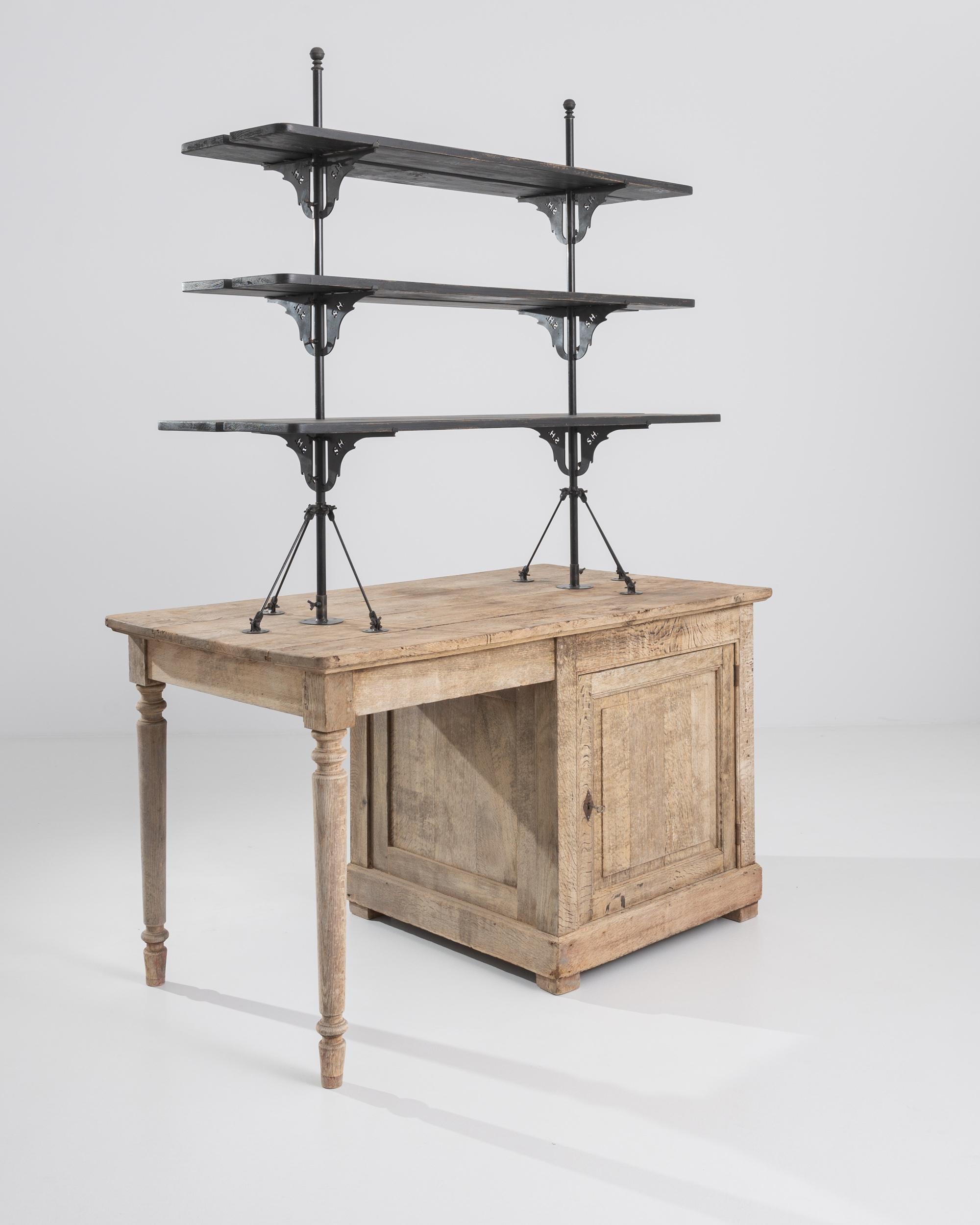 A 19th century bleached oak display cabinet from France. This cabinet consists of a large lower cabinet, upon which sits three top shelves. Its upper shelves extend above the wooden structure like masts on a ship, displaying a moody and unique
