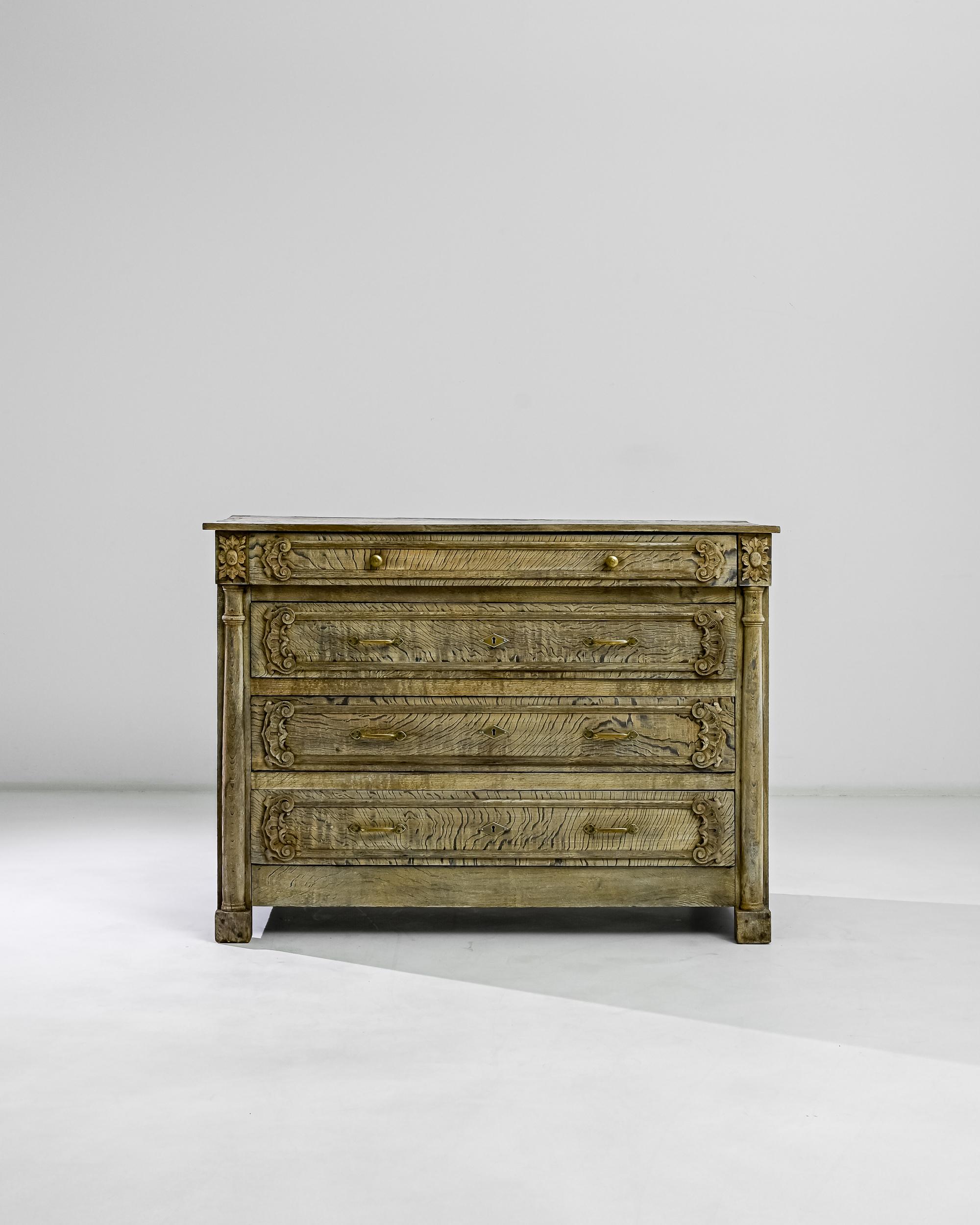 A bleached oak chest of drawers from France, produced circa 1850. A formal styled chest featuring four sliding drawers with original locks and keys and twin knobs of burnished metal. The painstaking, seamless craftsmanship of this chest is simply