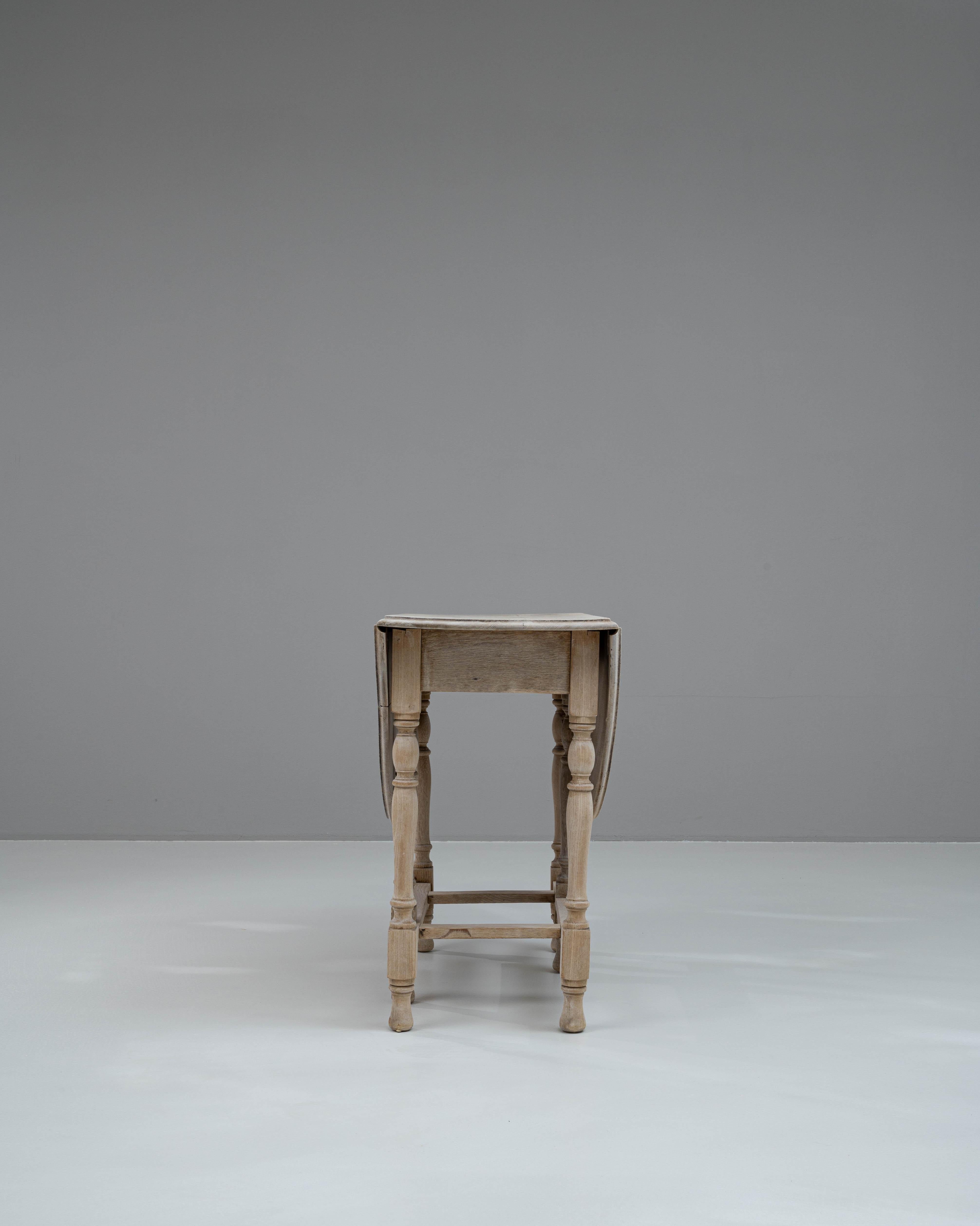 Cette table à abattant française du XIXe siècle est une pièce étonnante de mobilier ancien qui allie l'aspect pratique au charme intemporel. Fabriqué en chêne blanchi, il dégage une esthétique légère et rustique qui s'accorde avec différents styles