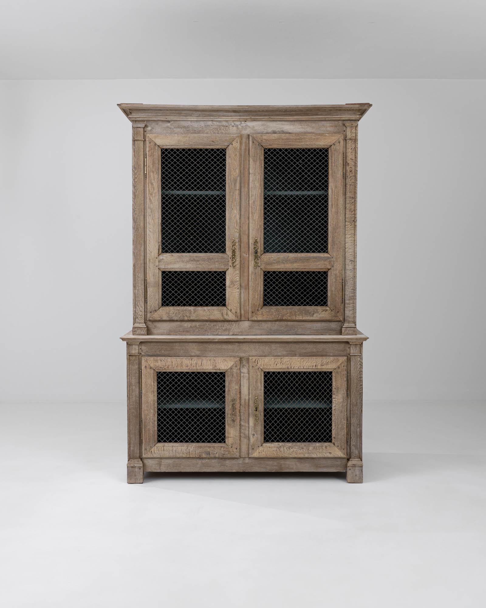 A sturdy two piece cabinet created in 19th century France. Stylishly enclosing a generous storage space, this elegant cabinet exudes a sense of grace and approachable familiarity. Its wire mesh doors conjure an image of linens dried in the summer