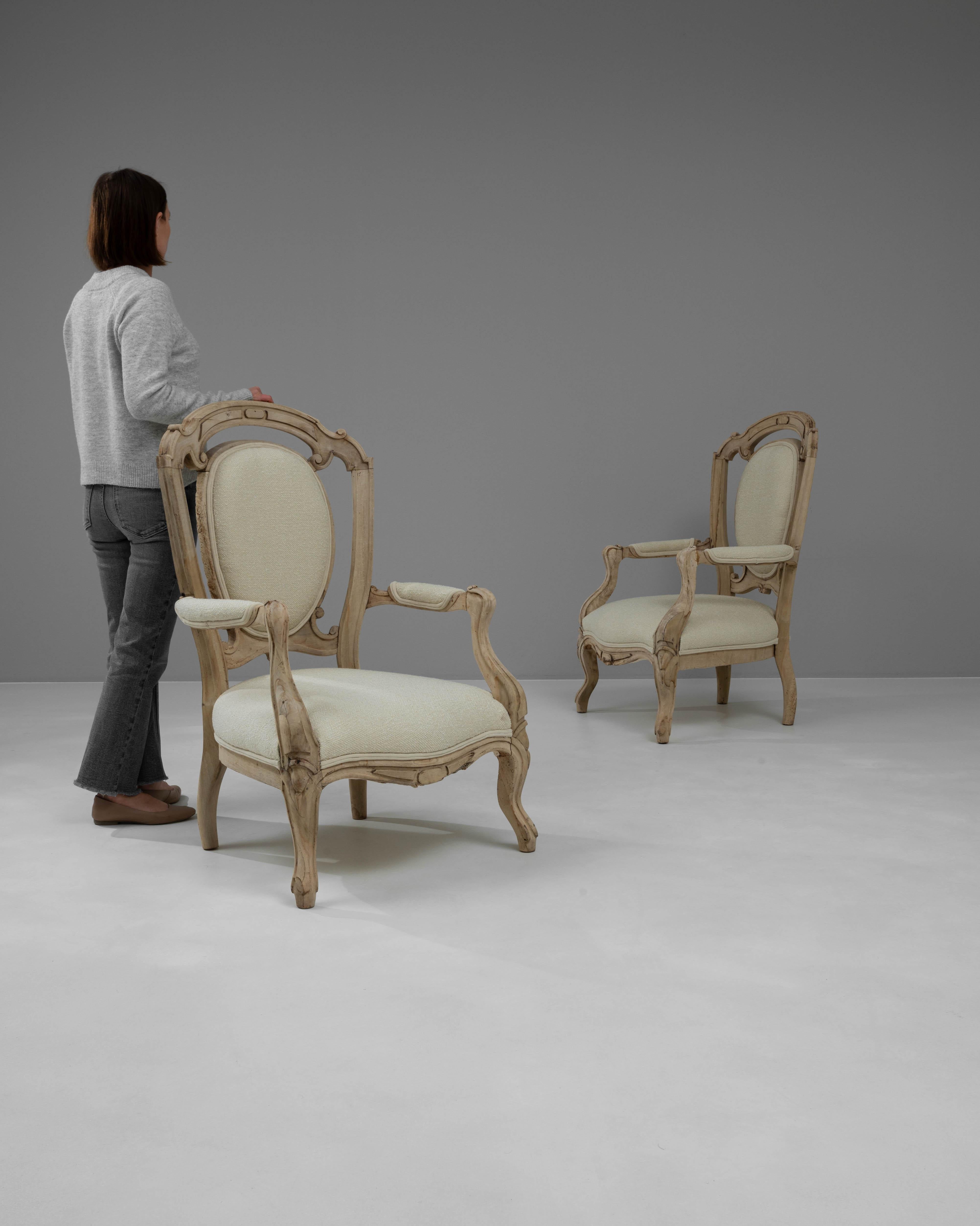 Enhance your living space with this exquisite pair of 19th Century French Bleached Oak Upholstered Armchairs, each radiating a timeless elegance and old-world charm. Crafted from beautifully bleached oak, these chairs showcase the natural beauty and