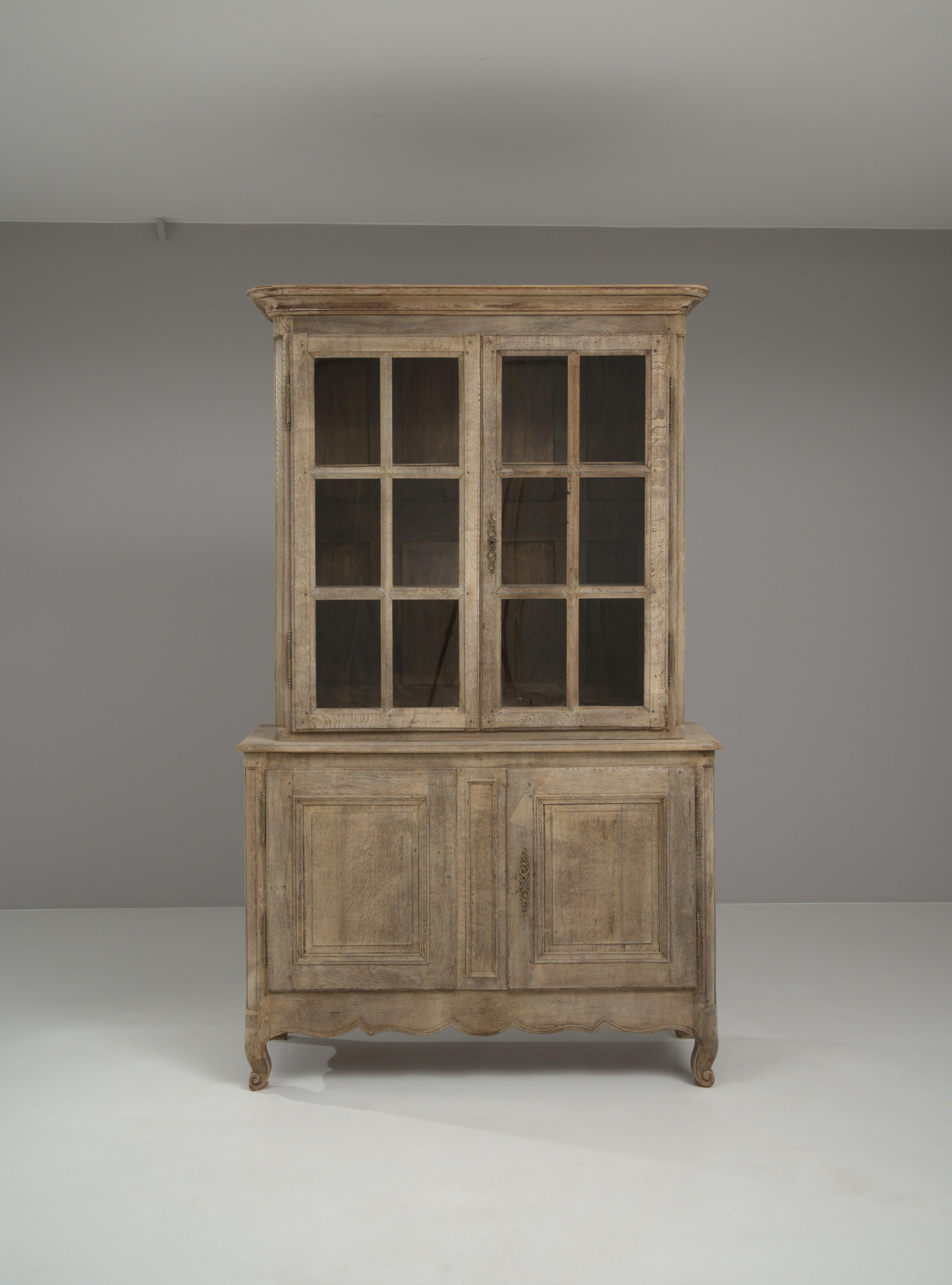 Enhance your living space with the timeless elegance of this 19th Century French Bleached Oak Vitrine. This exquisite piece, crafted from solid oak, has been meticulously bleached to reveal the wood's natural beauty, creating a light and airy