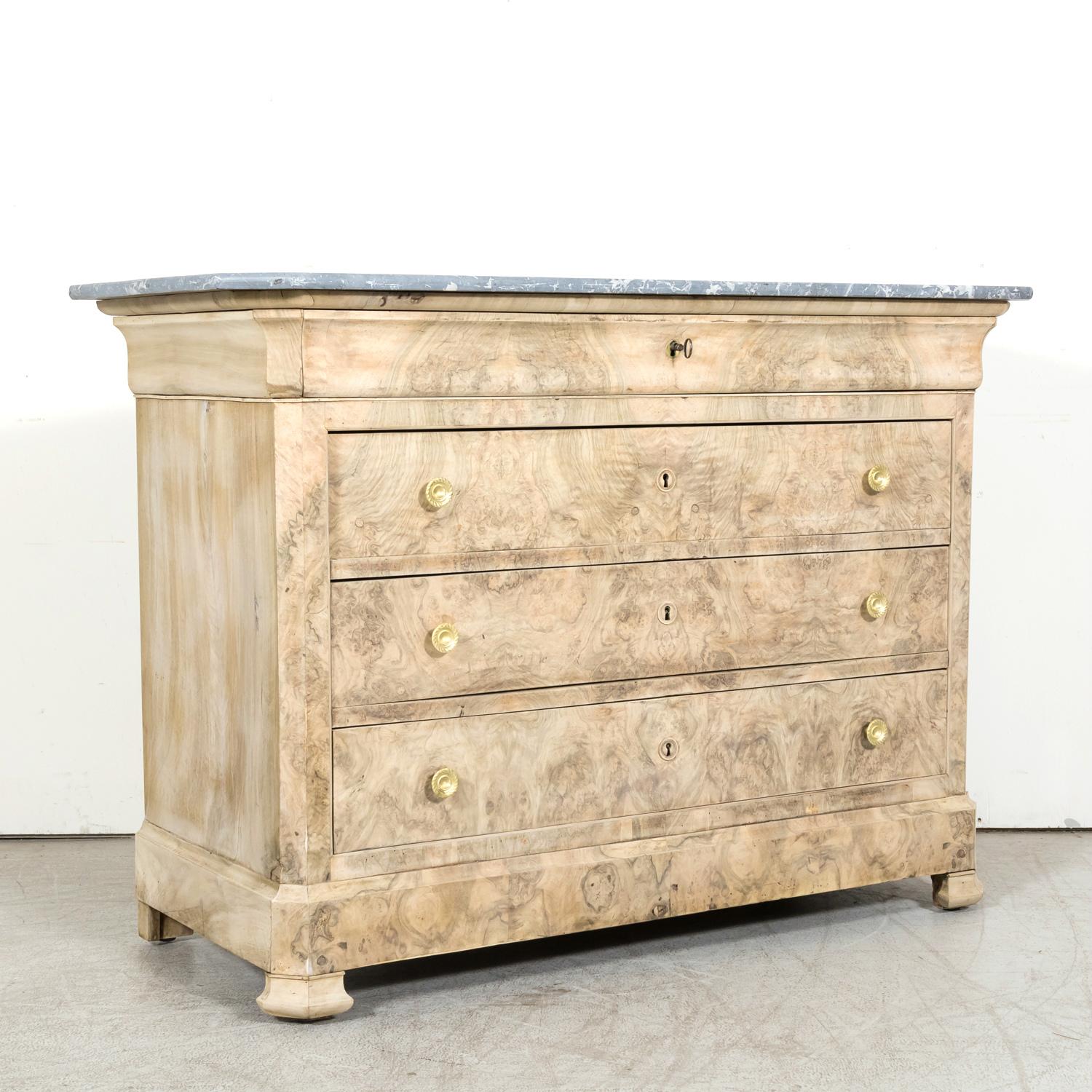 A handsome 19th century French Louis Philippe style four-drawer bleached commode, circa 1880s. Handcrafted of walnut and meticulously bookmatched burled walnut, this handsome commode is complimented by its original Saint Anne gray marble top with an