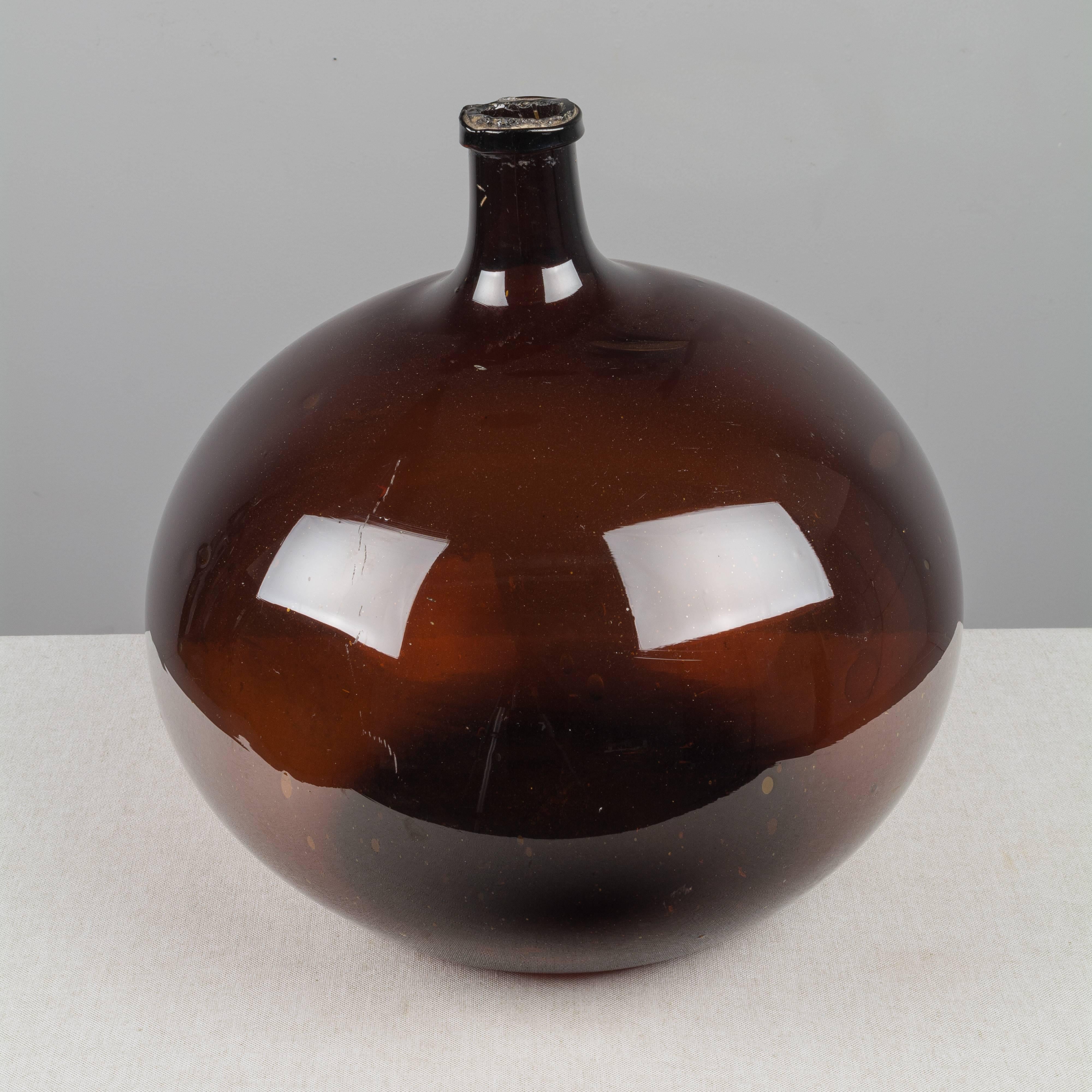 A large 19th century French globular form amber demijohn bottle with air bubbles typical of handblown glass. Please refer to photos for more details. We have a large selection of French antiques at Olivier Fleury, Inc.  Please visit our showroom in
