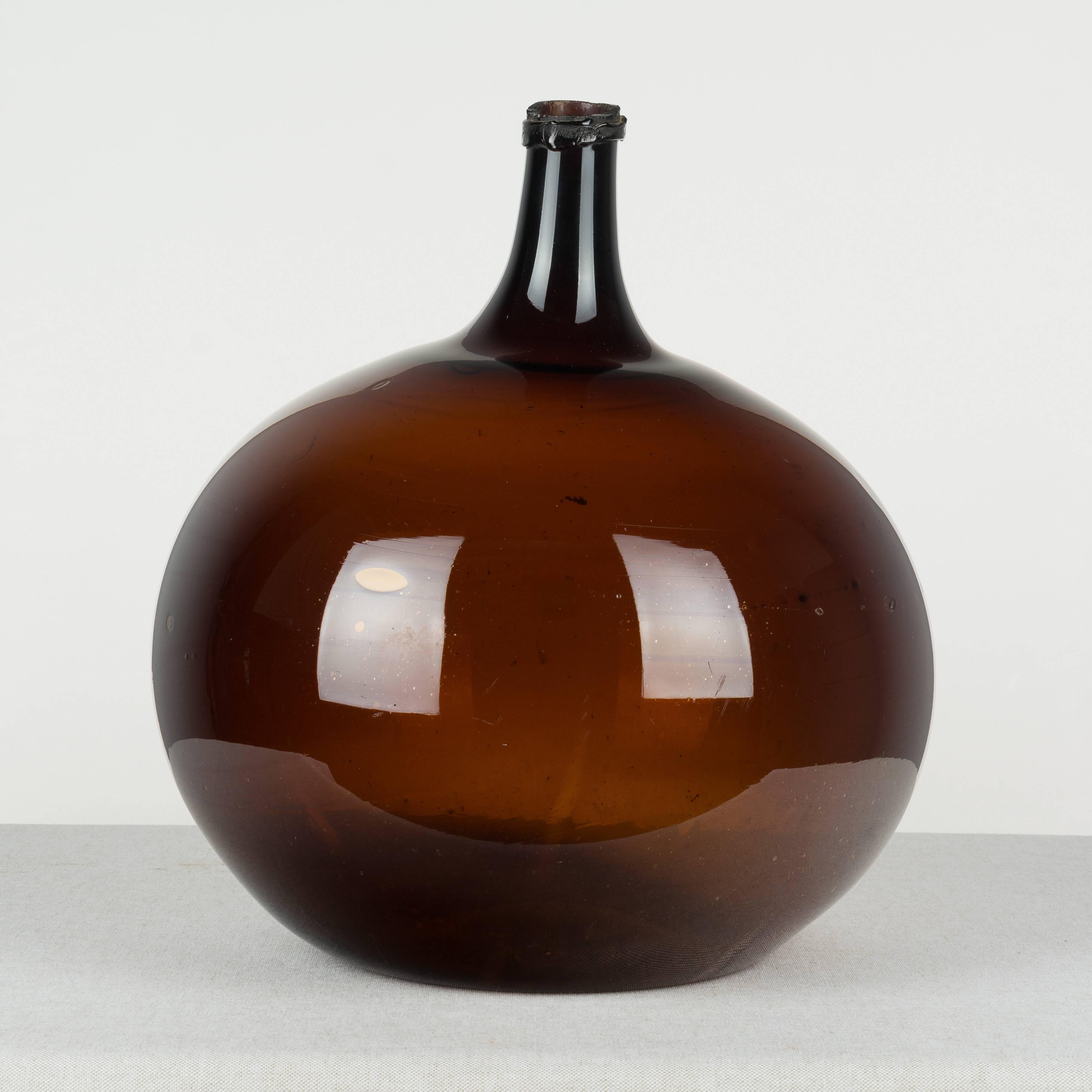 A large 19th century French globular form amber demijohn bottle with air bubbles typical of handblown glass. Please refer to photos for more details. We have a large selection of French antiques at Olivier Fleury, Inc.  Please visit our showroom in