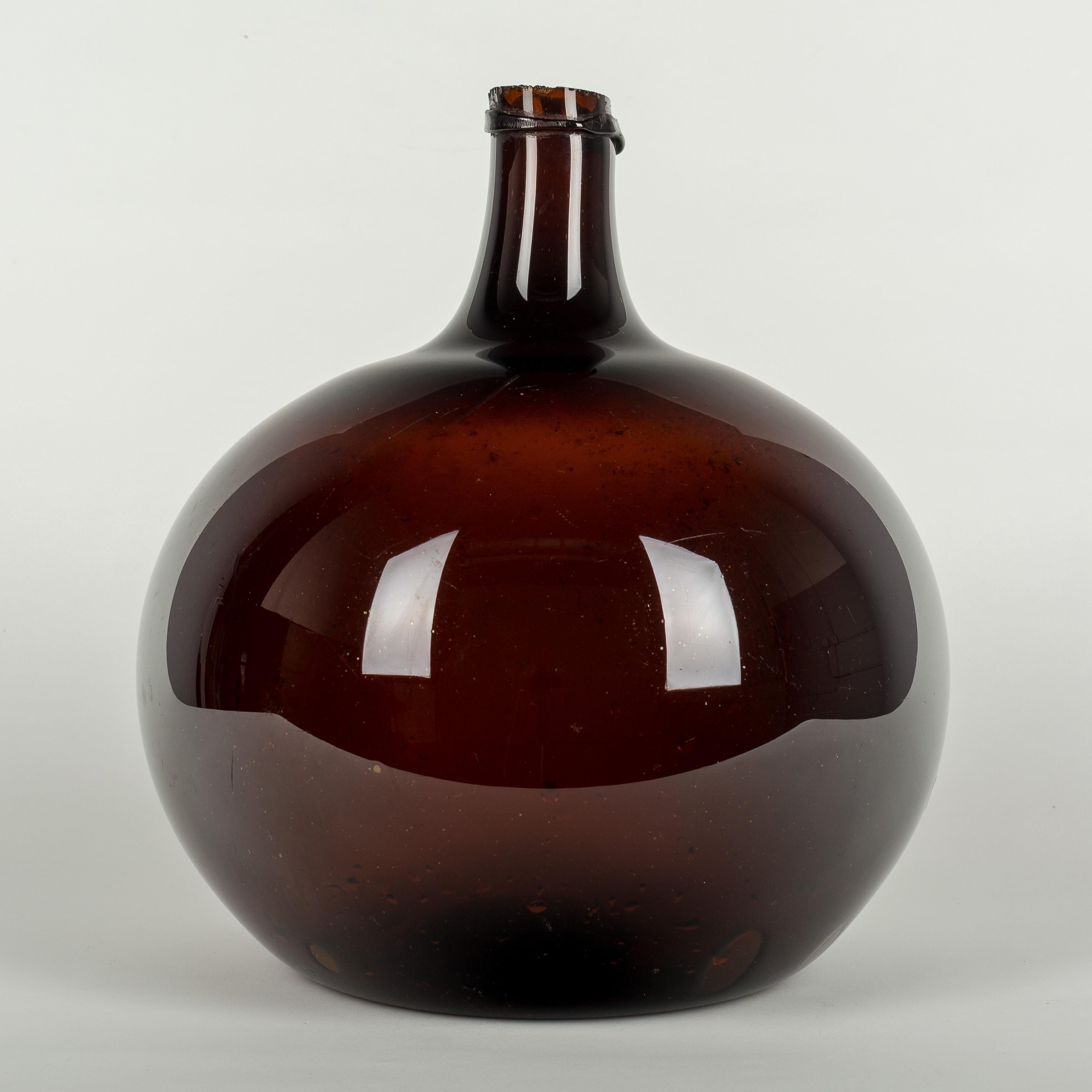 A large 19th century French globular form amber demijohn bottle with air bubbles typical of hand blown glass.