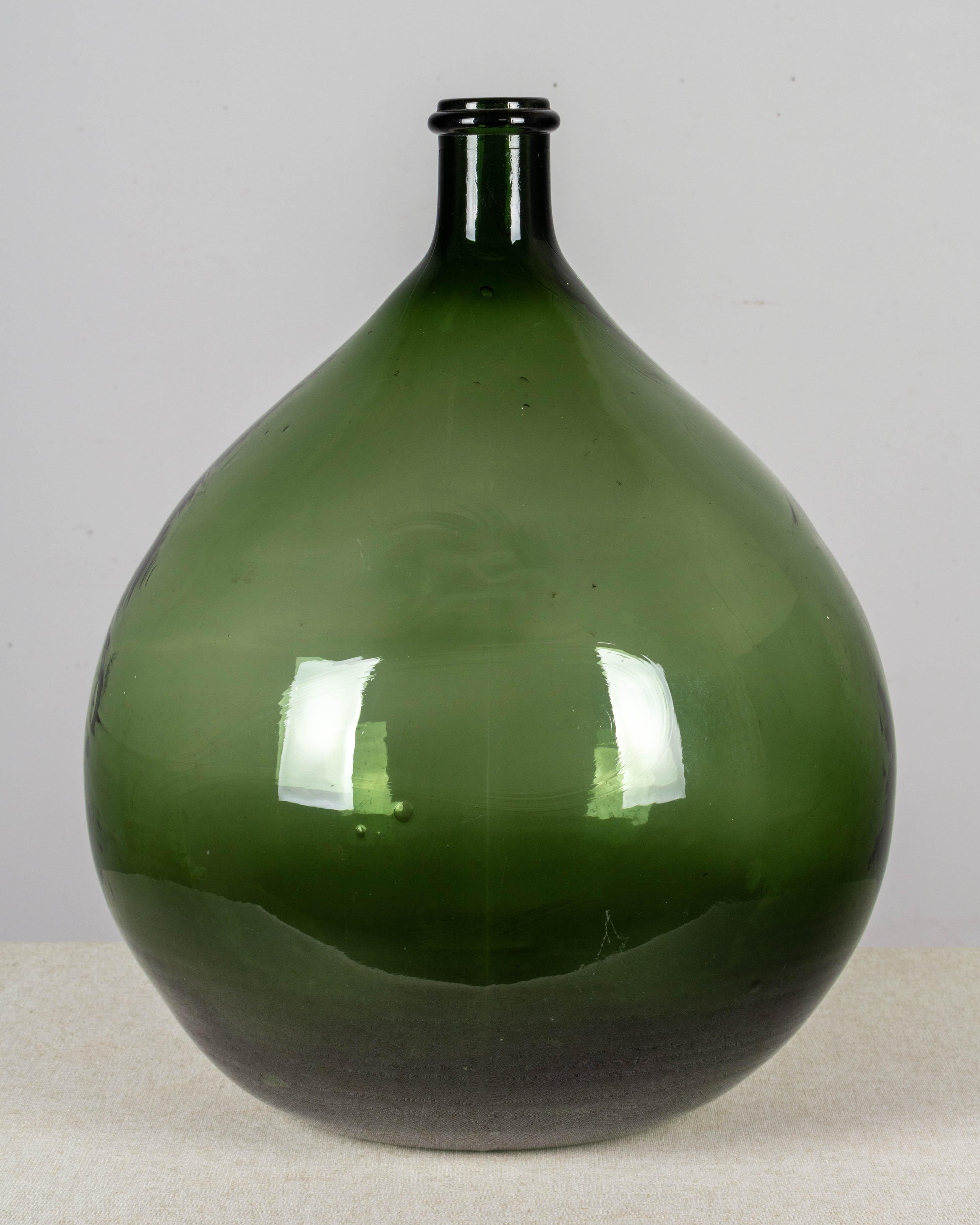 A large 19th century French globular form hand blown green glass dame Jeanne, or demijohn bottle. Capacity: 25 liters. Weight: 9 lbs.