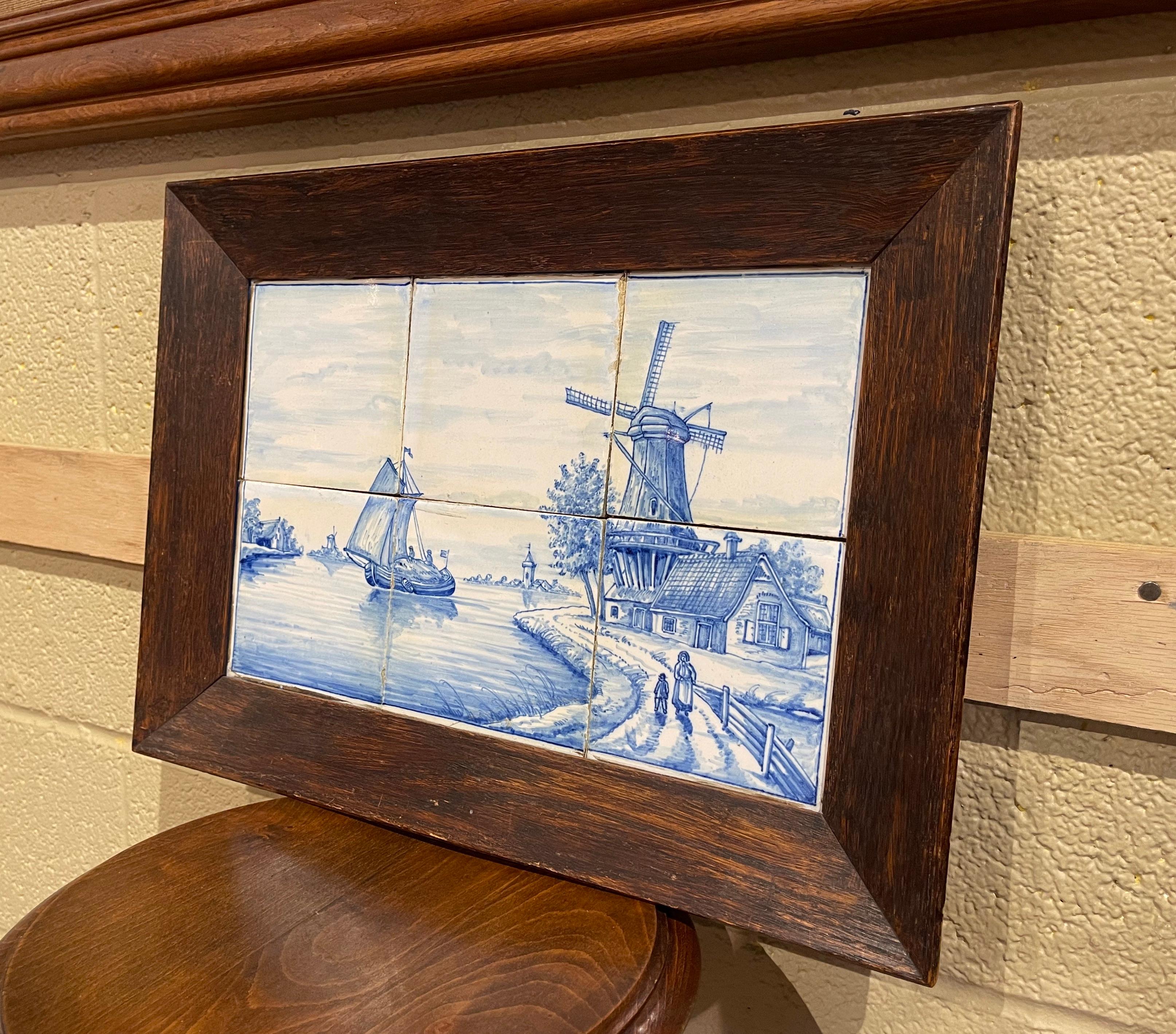 The elegant antique ceramic tile frame was created in France, circa 1860. The wall decor is set inside a carved oak frame, and features six hand painted faience tiles with illustrations typical of the traditional Delft style and coloration; the
