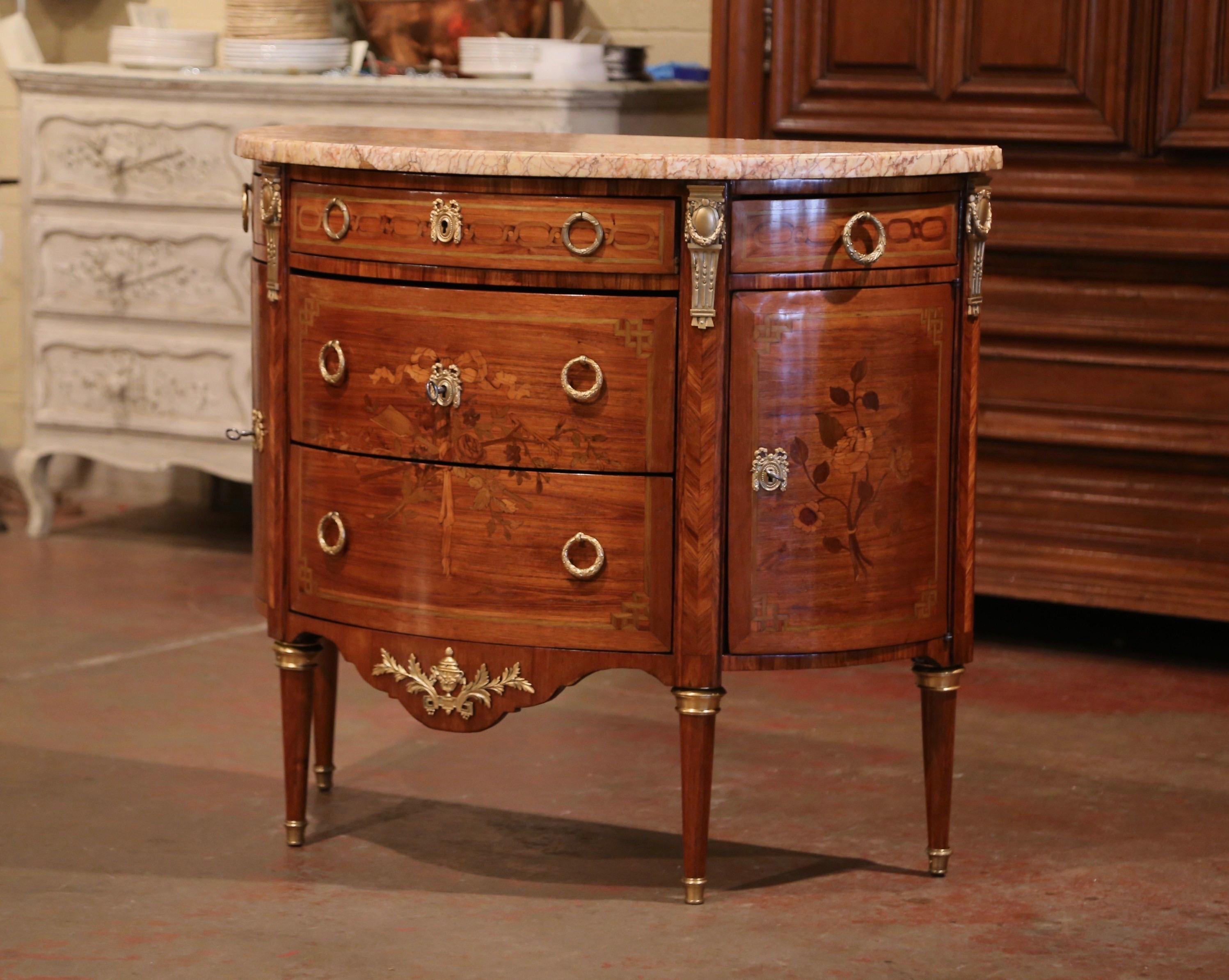 Crafted in Paris, circa 1870, the fruitwood commode shaped as a demilune (or half moon), stands on tapered and fluted legs decorated at the base and shoulders with brass caps. The cabinet features three bombe drawers across the front and two curved