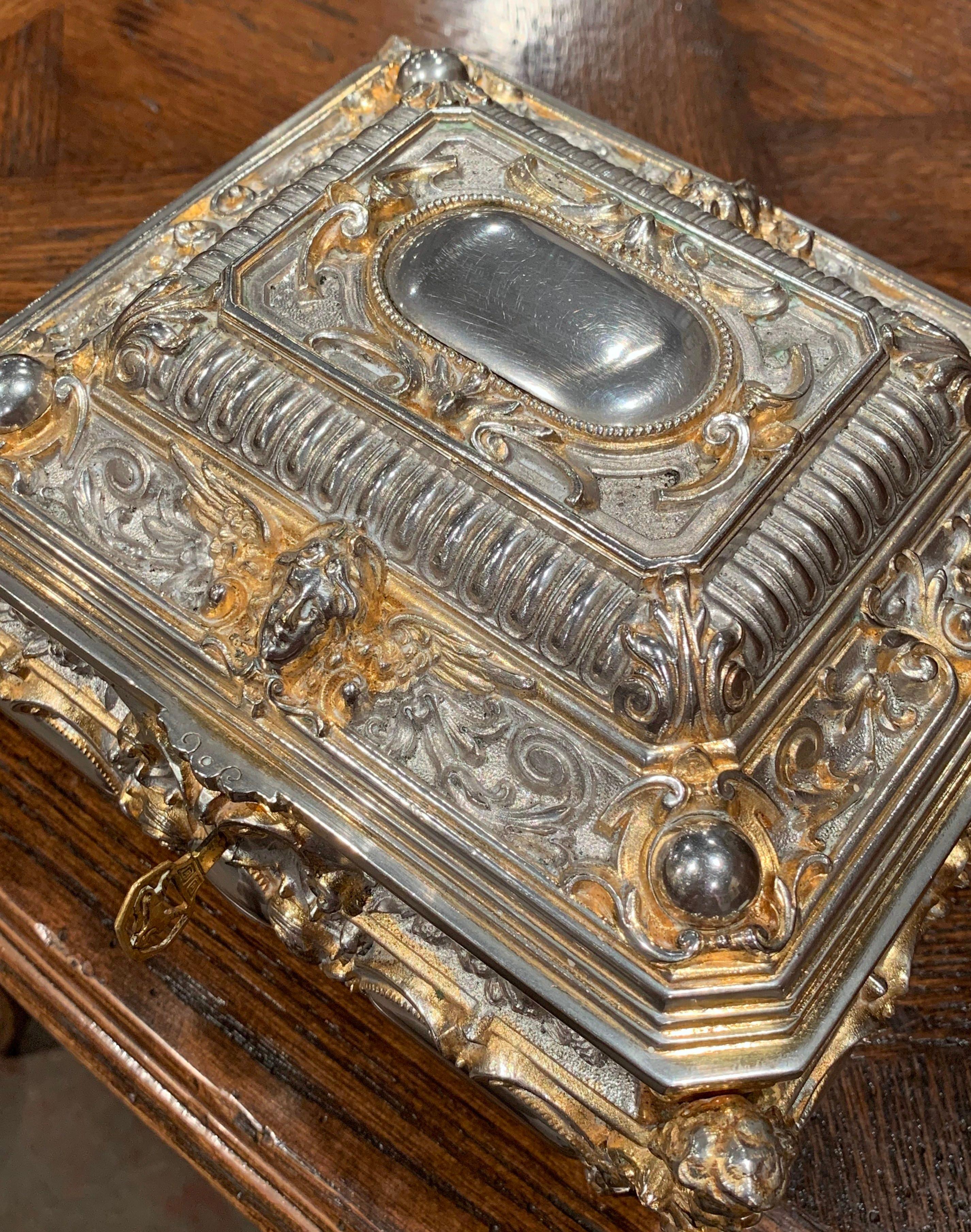 Place this elegant antique silver box in your master bath to keep your jewelry safe and organized. Crafted in France, circa 1880, the two-tone ornate rectangular casket sits on four scroll feet and has four bow sides over a raised top; the box