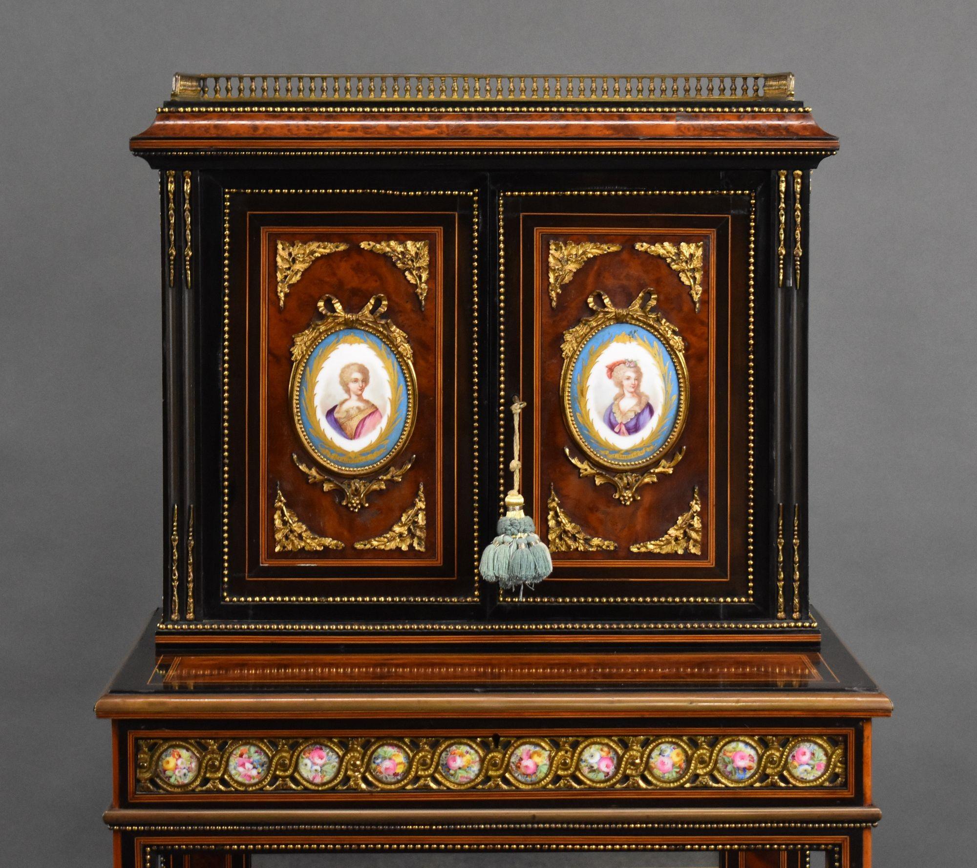 For sale is a French 19th century Amboyna and Ebony Cabinet, with three quarter balustrade gallery, above two panelled doors set with Paris porcelain portrait panels upon a two tier open Stand with gilt metal mounts and a porcelain panelled frieze.