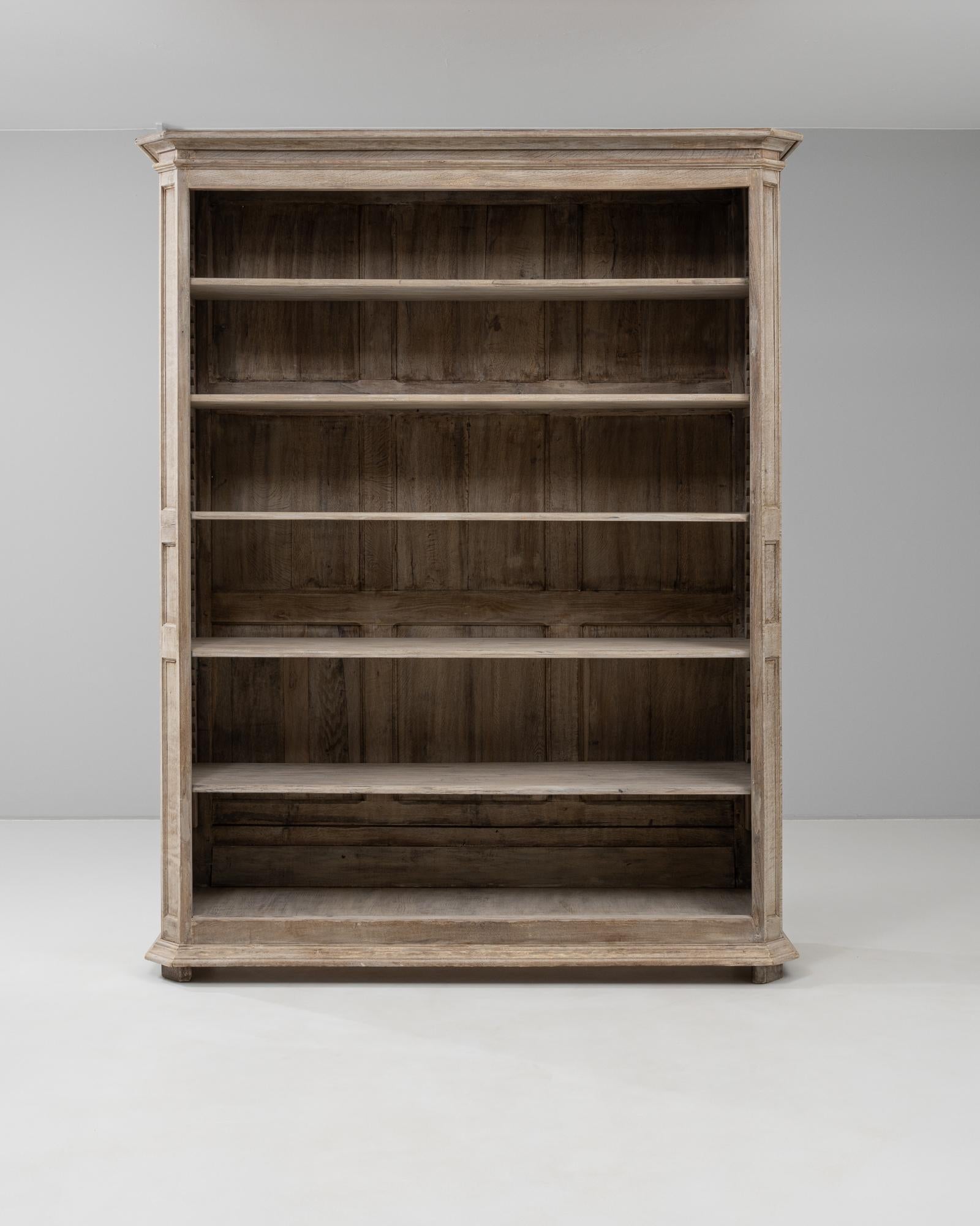 This 19th Century French bookcase cabinet showcases timeless craftsmanship with its stately proportions and understated elegance. Made from solid oak with a softly weathered, bleached finish, the cabinet features five adjustable shelves set within a