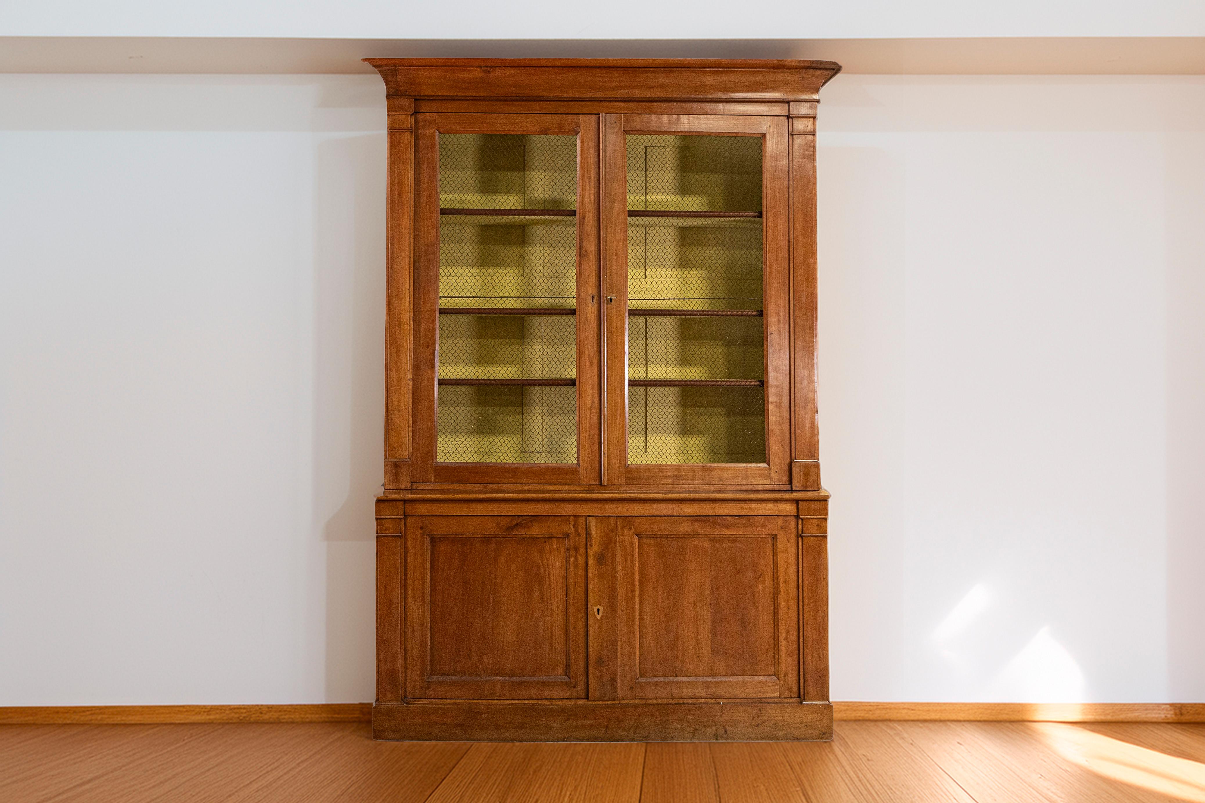 This 19th-century French bookcase is a stunning example of both elegance and practicality, crafted from solid walnut with a warm, rich patina that highlights the wood’s natural grain. The upper section features wire mesh doors instead of glass, a