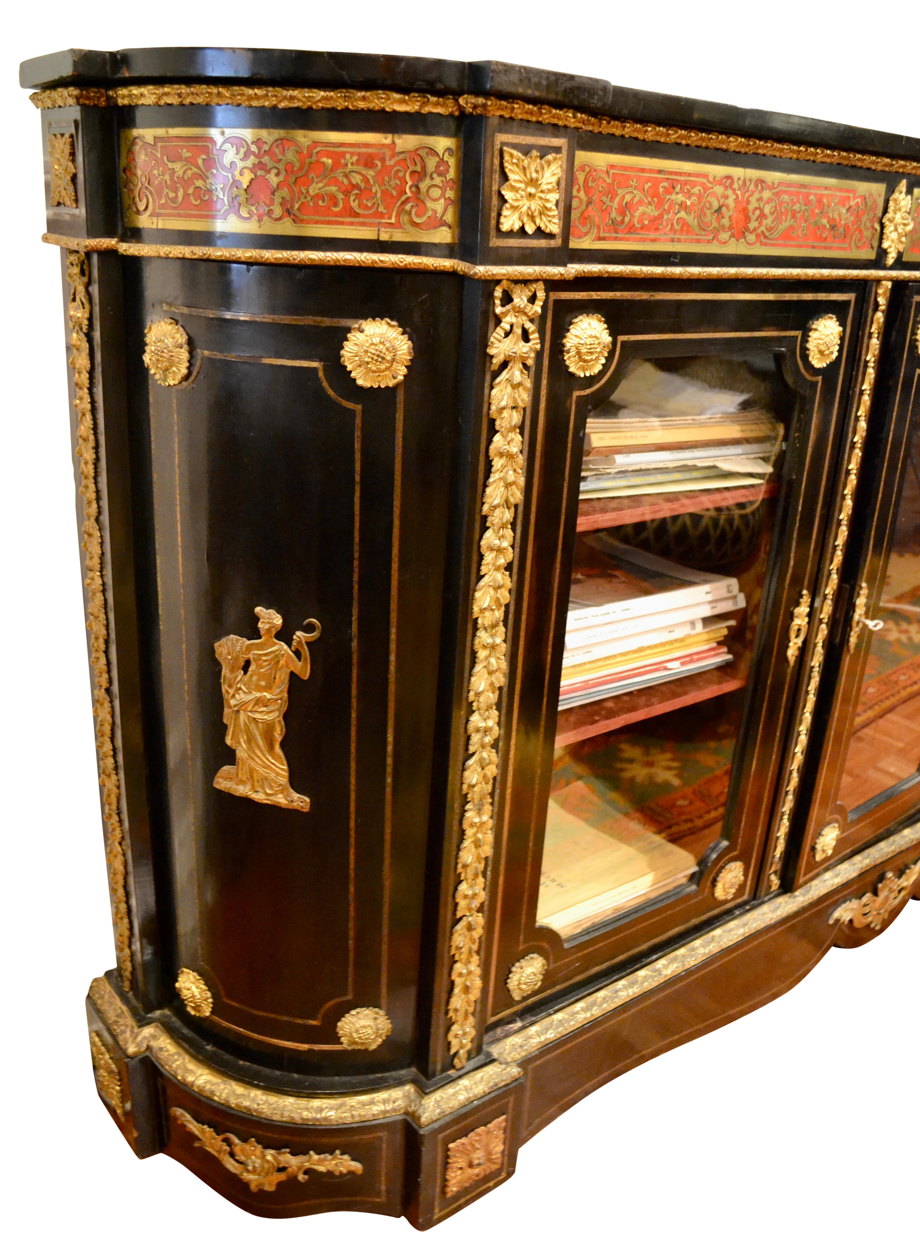 A handsome bookcase or china cabinet made in France in the last half of the 19th century. The case is in ebonized wood (including the top), and is curved at each side. There are three front doors with glass fronts and brass trim which open to reveal