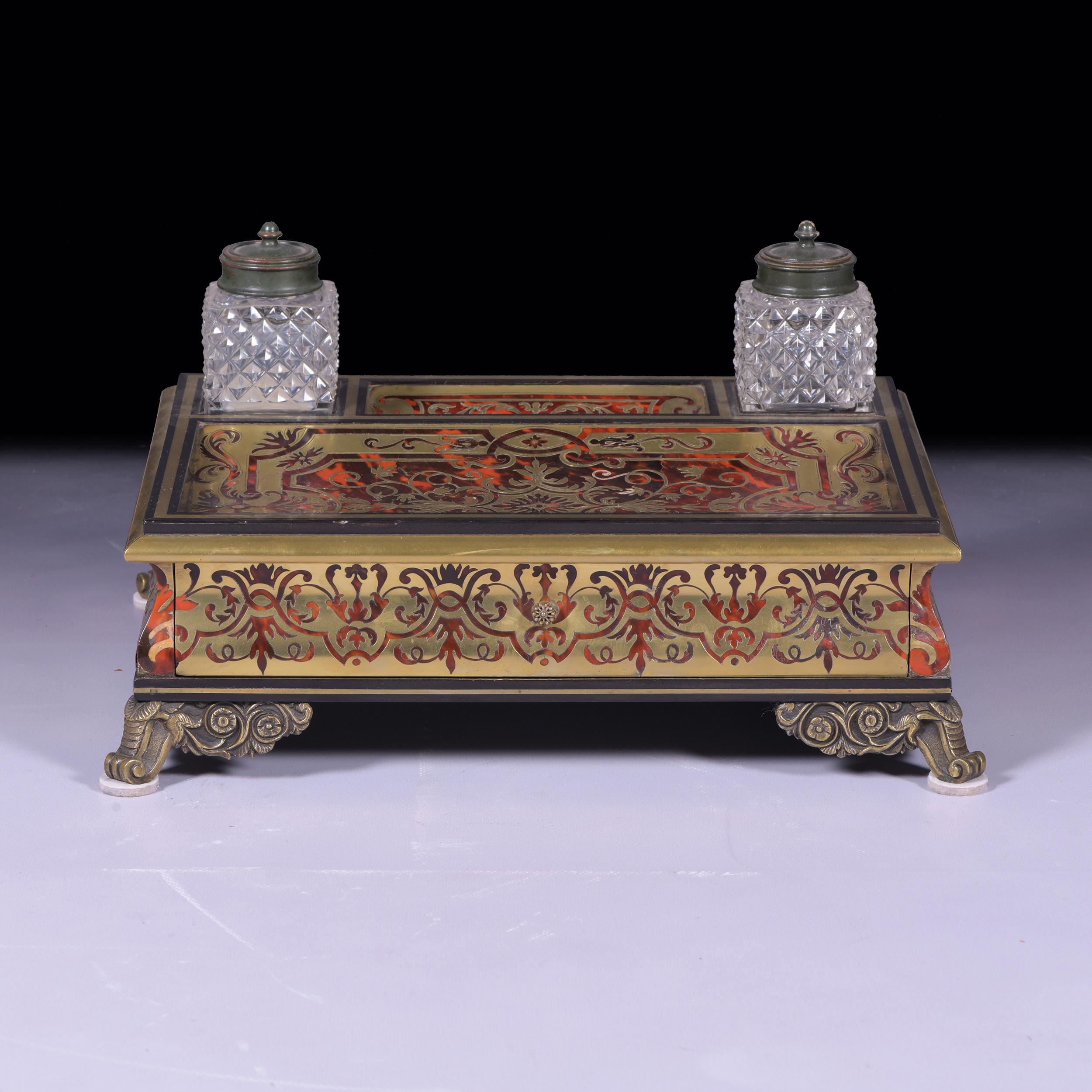 An exceptional 19th century Boulle work inkwell, of rectangular form, fitted with two cut glass ink wells and covers, with dished pen tray, decorated with cut brass arabesques above a long frieze stationary drawer on cast ormolu feet.

Circa