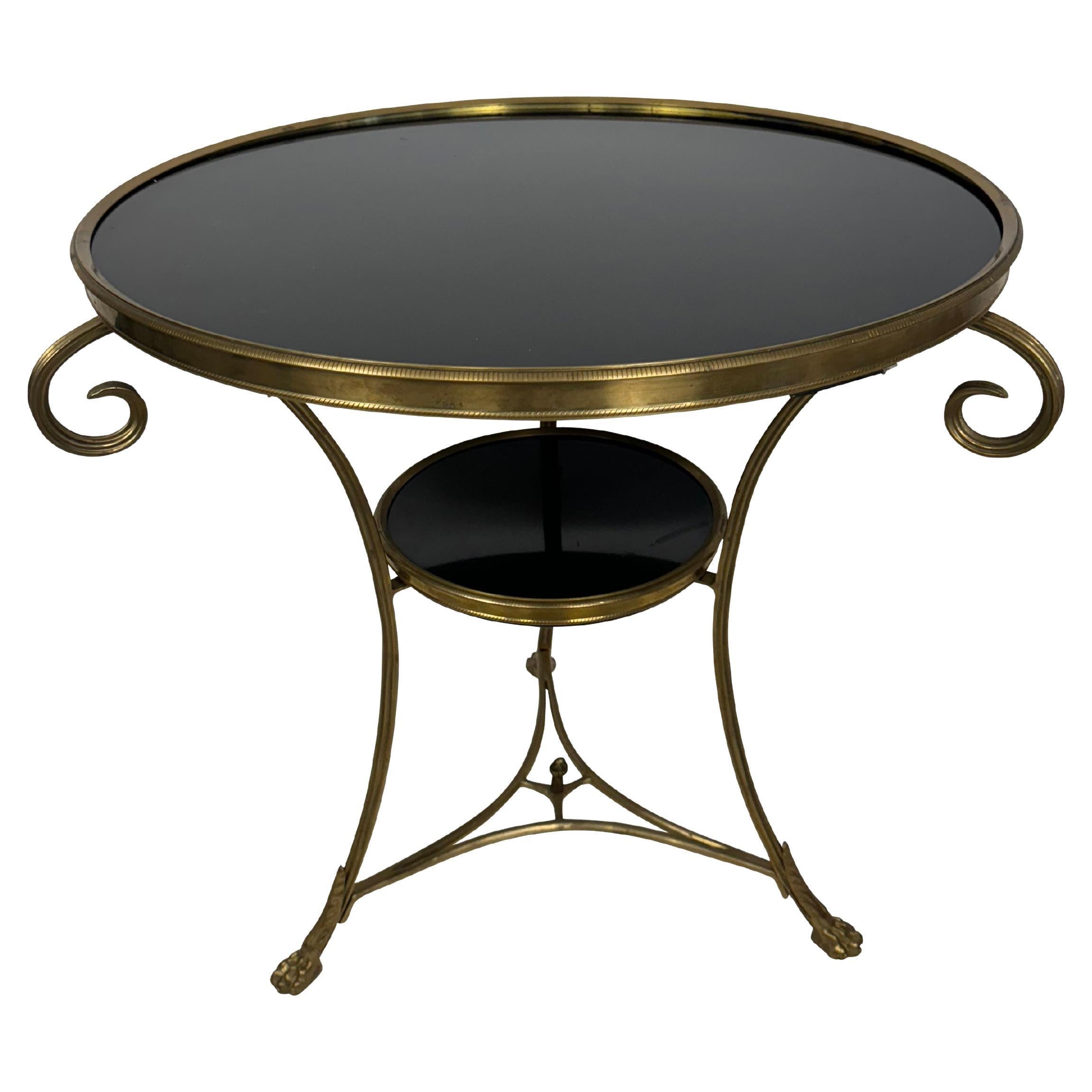 Table d'appoint en laiton de style Louis XVI, avec trois pieds supportant un plateau en marbre noir et une étagère, avec une traverse inférieure. Dimensions : 30 pouces de diamètre par 27 pouces.  Un ajout élégant et classique à tout salon ou
