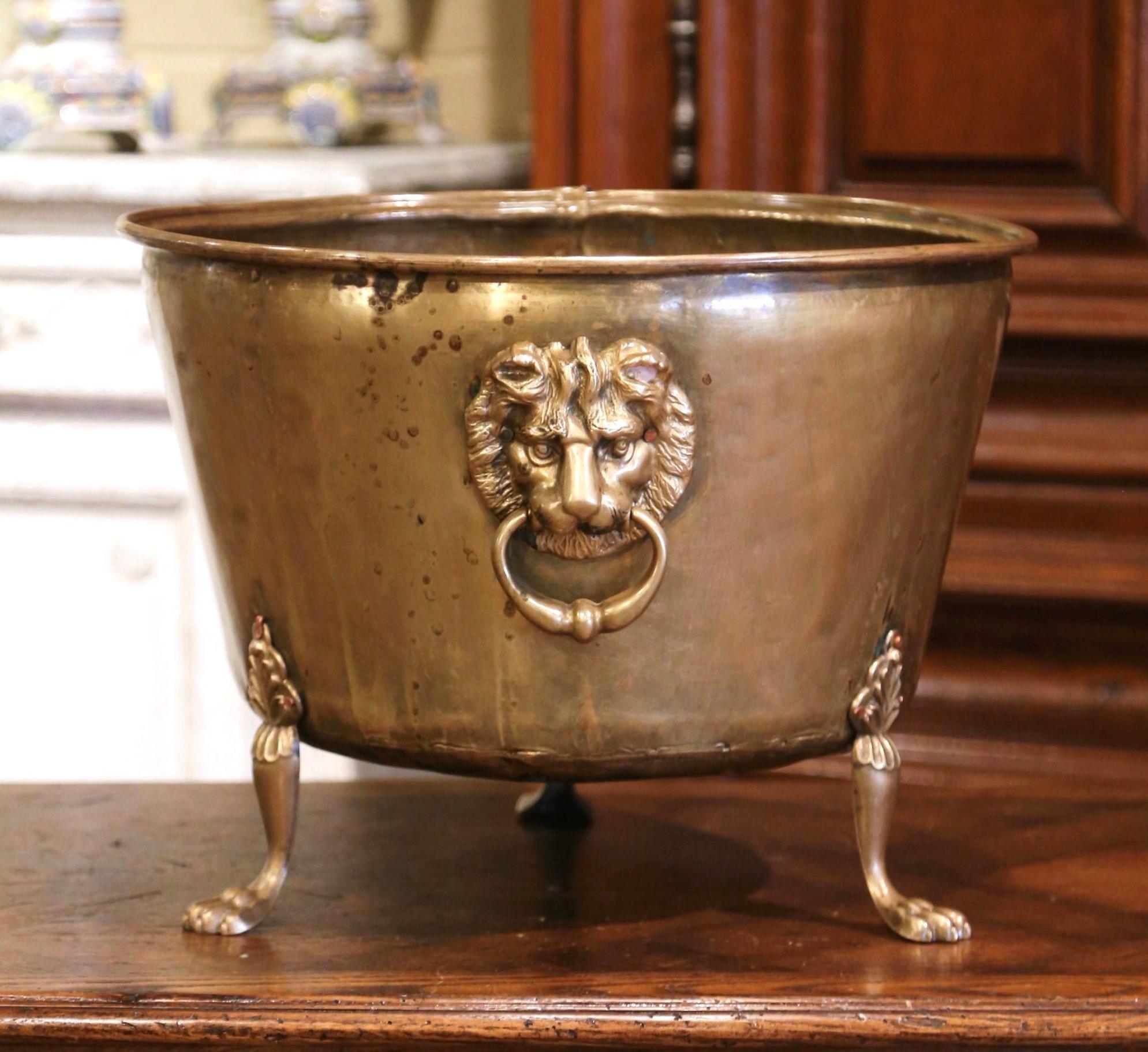 This large brass planter was crafted in France, circa 1880. Round in shape, the decorative cache pot stands on small paw feet and is embellished with lion heads figures handles. The large planter is in excellent condition with a rich patinated brass