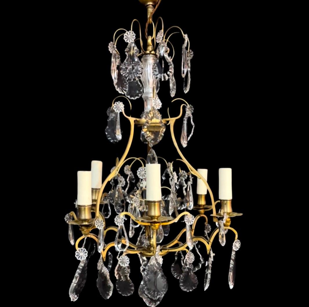 This exquisite 19th-century French brass cage chandelier is a masterpiece of craftsmanship, adorned with resplendent crystal drops, French Slab plaquets, and delicate French pear drops, all intricately joined by glass rosettes.

The central shaft,