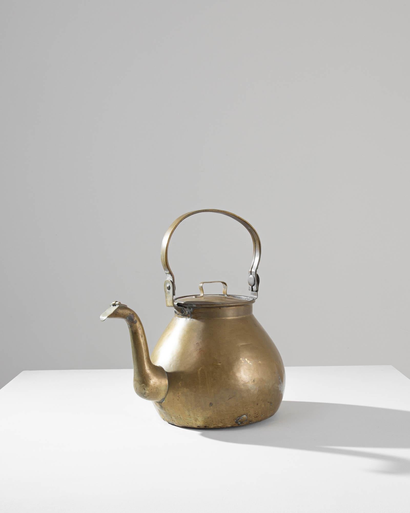 This elegant antique kettle makes a delightful addition to a kitchen. Made in France in the 1800s, the tall handle may once have been used to hang over an open fire. The graceful curvature of the spout – clapped shut with a small metal plate – lends