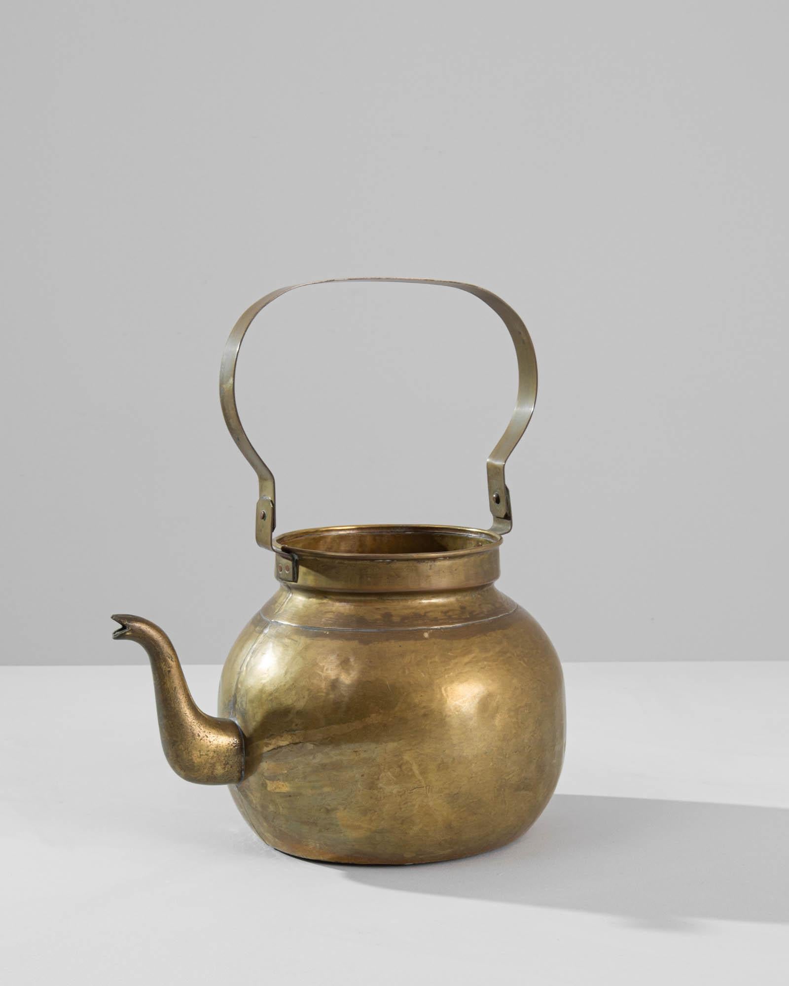 This elegant antique kettle makes a delightful addition to a kitchen. Made in France in the 1800s, the tall handle may once have been used to hang over an open fire. The graceful curvature of the spout lends this pragmatic object an air of