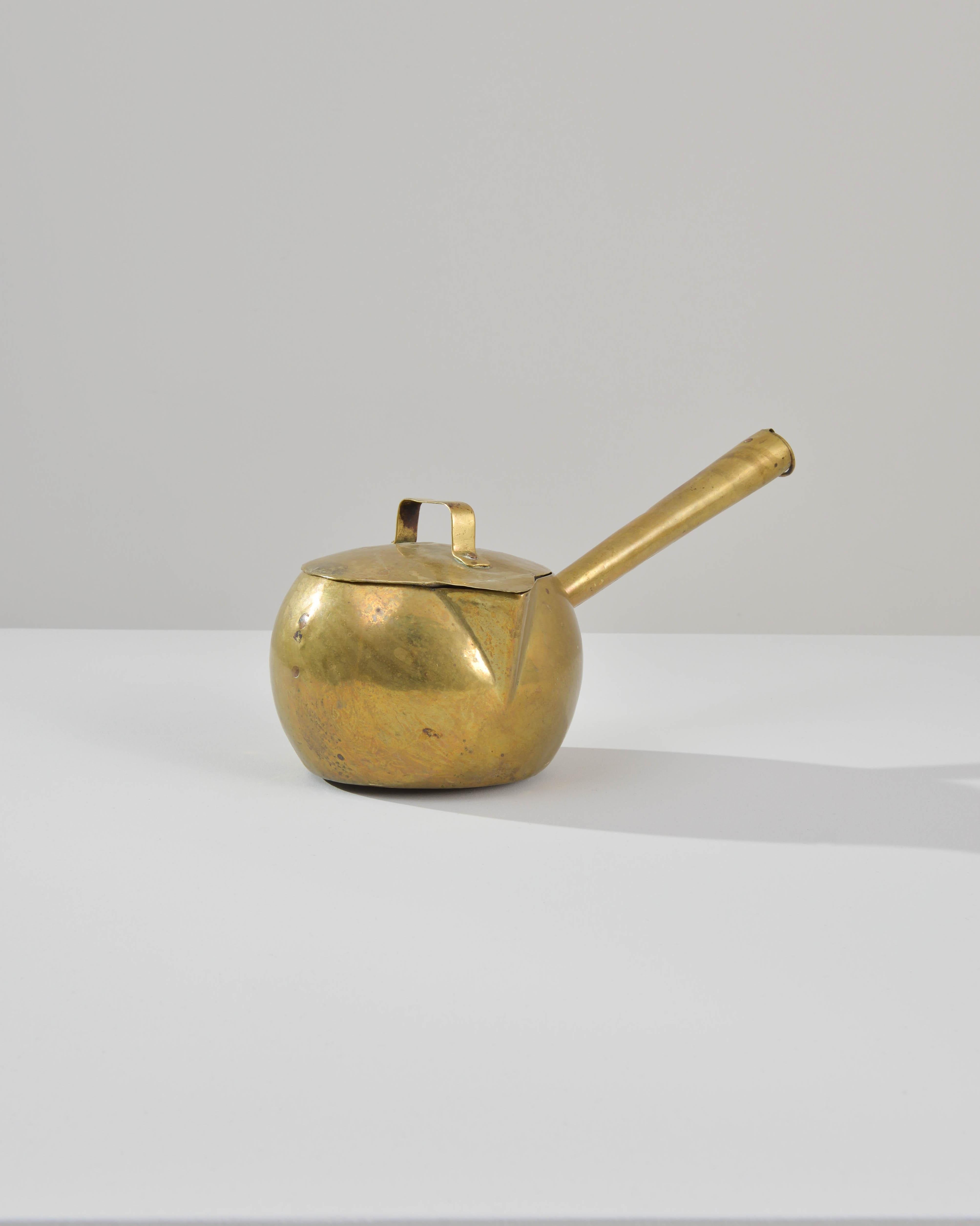 The charming shape and bright finish of this brass pot make for a delightful kitchen accent. Made in France in the 1800s, the sides of the pot are gently rounded, giving it a spherical appearance. A neat triangular spout, like the beak of a small