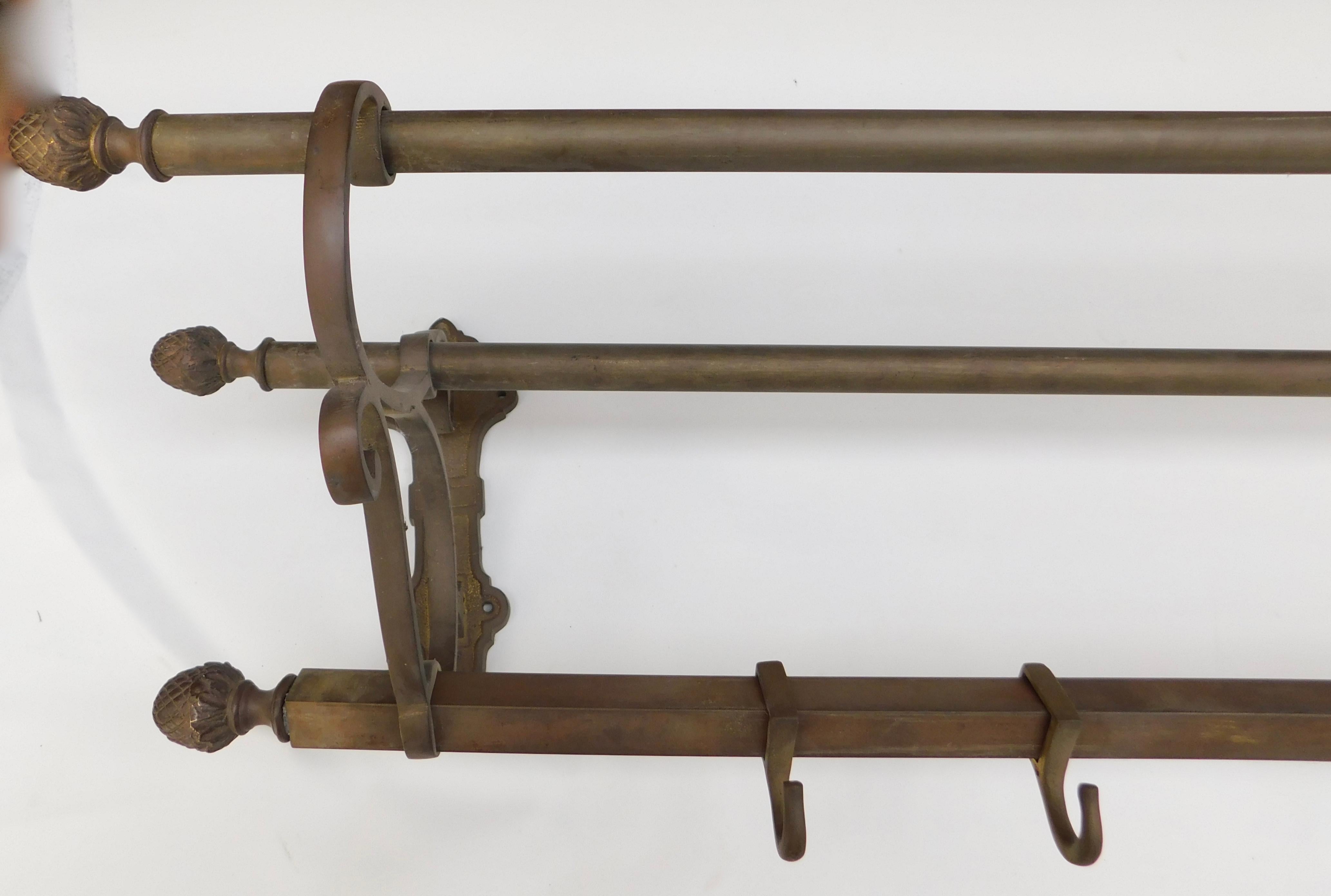 French brass shelf /rack with a beautiful patina achieved with time and use. Sliding hooks and pineapple end finials are some of the details that make this a decorative and flexible piece, circa 1880. Great to use for coats, hats and handbags, but