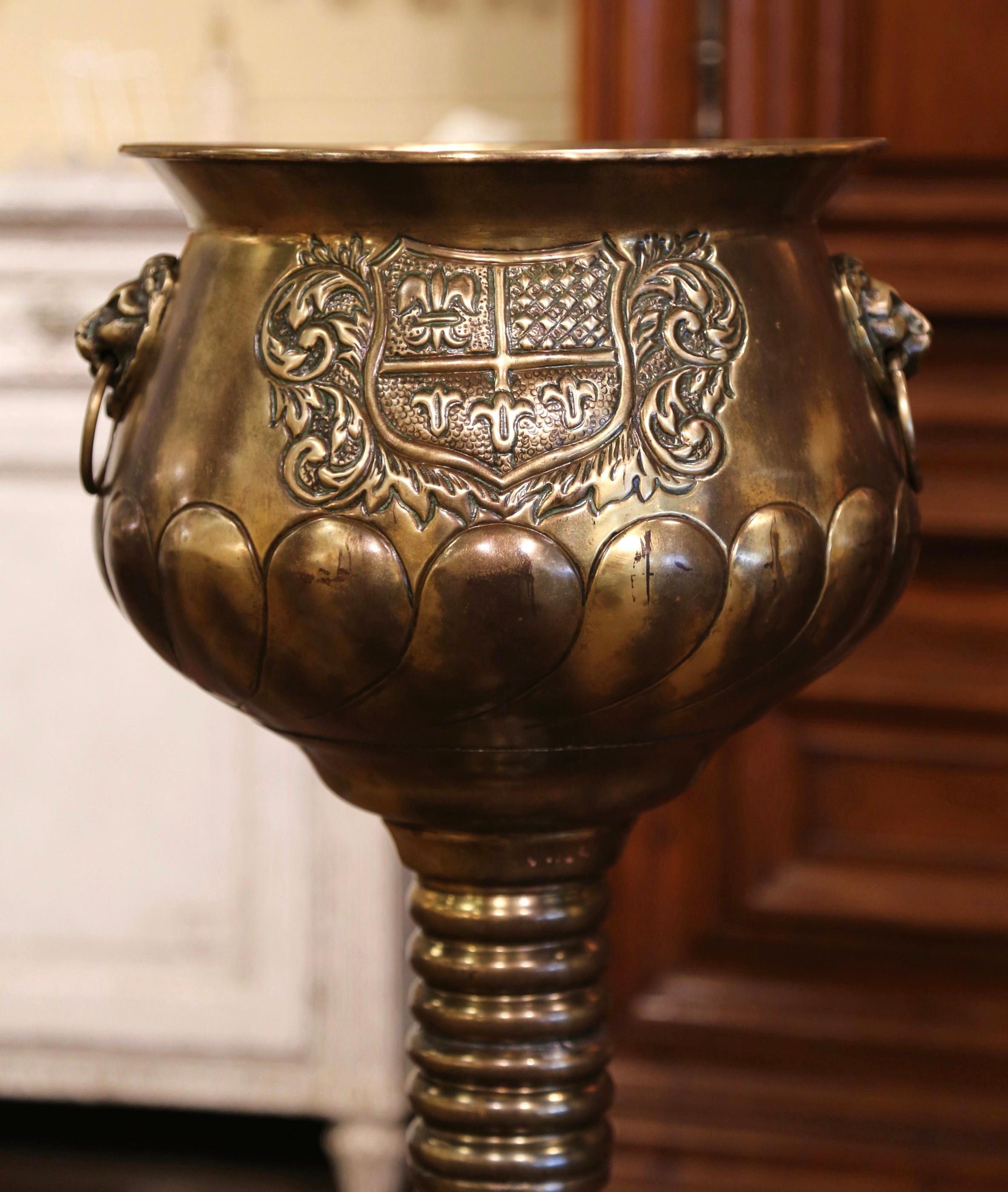 This large antique brass planter was crafted in France, circa 1880. Round in shape, the decorative cache pot stands on an integral circular base decorated with repousse acanthus leaves, over a long stem embellished with turned ring motifs. The